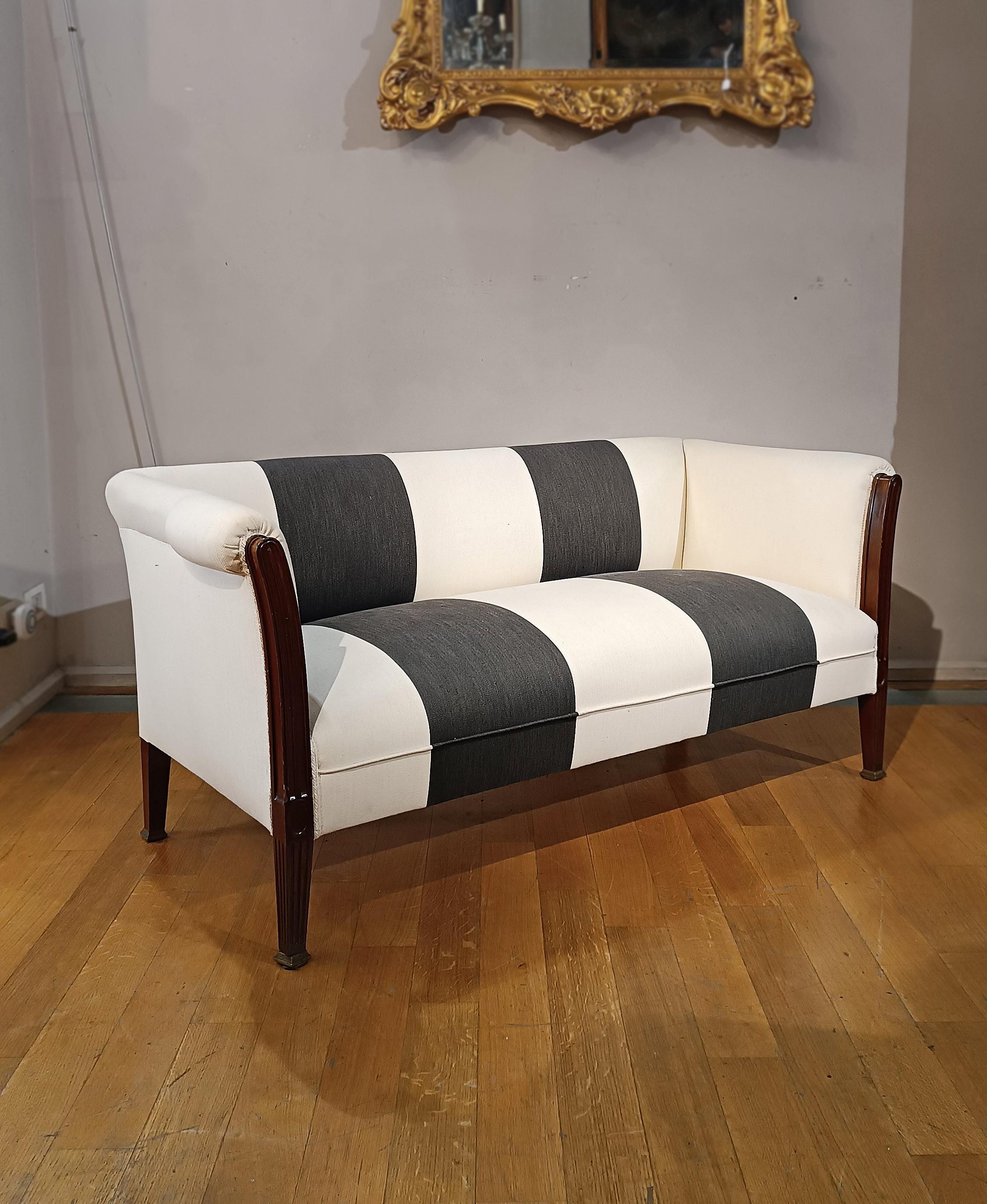 Elegantes Sofa aus massivem, geschnitztem Nussbaumholz. Das Sofa ist klein und hat pyramidenstumpfförmige Füße und Füße, die mit kleinen Sockeln aus Bronzeguss enden. Außerdem wurde er mit einem neuen zweifarbigen Leinenbezug in Weiß und Grau neu