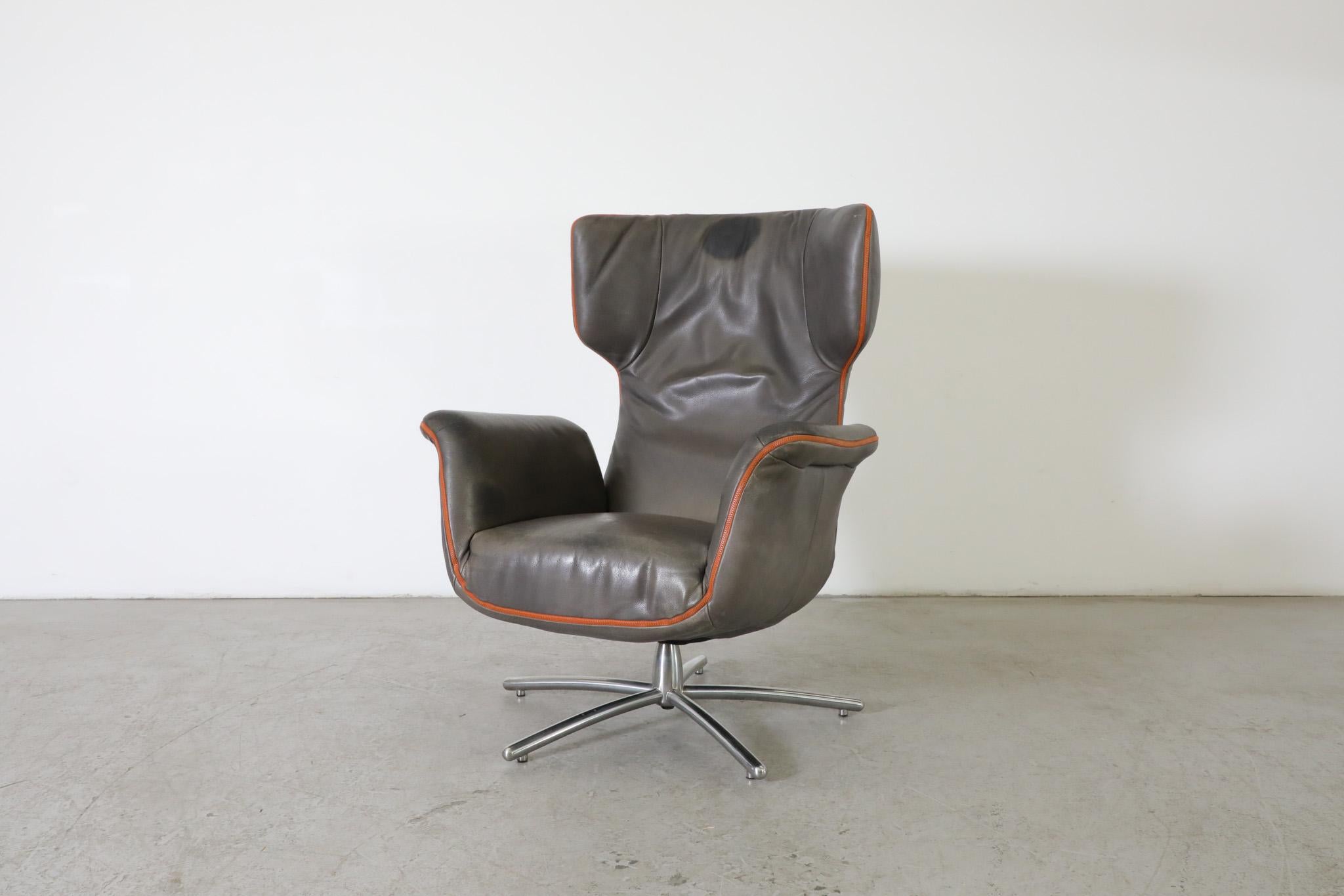 MOD 'First Class Armchair' from Label Vandenberg by Gerard van den Berg, 2014. An impressive gray leather swivel chair with burnt orange zipper and piping on a chrome multi-foot base. A relaxed swivel lounge chair perfect as a playful desk or