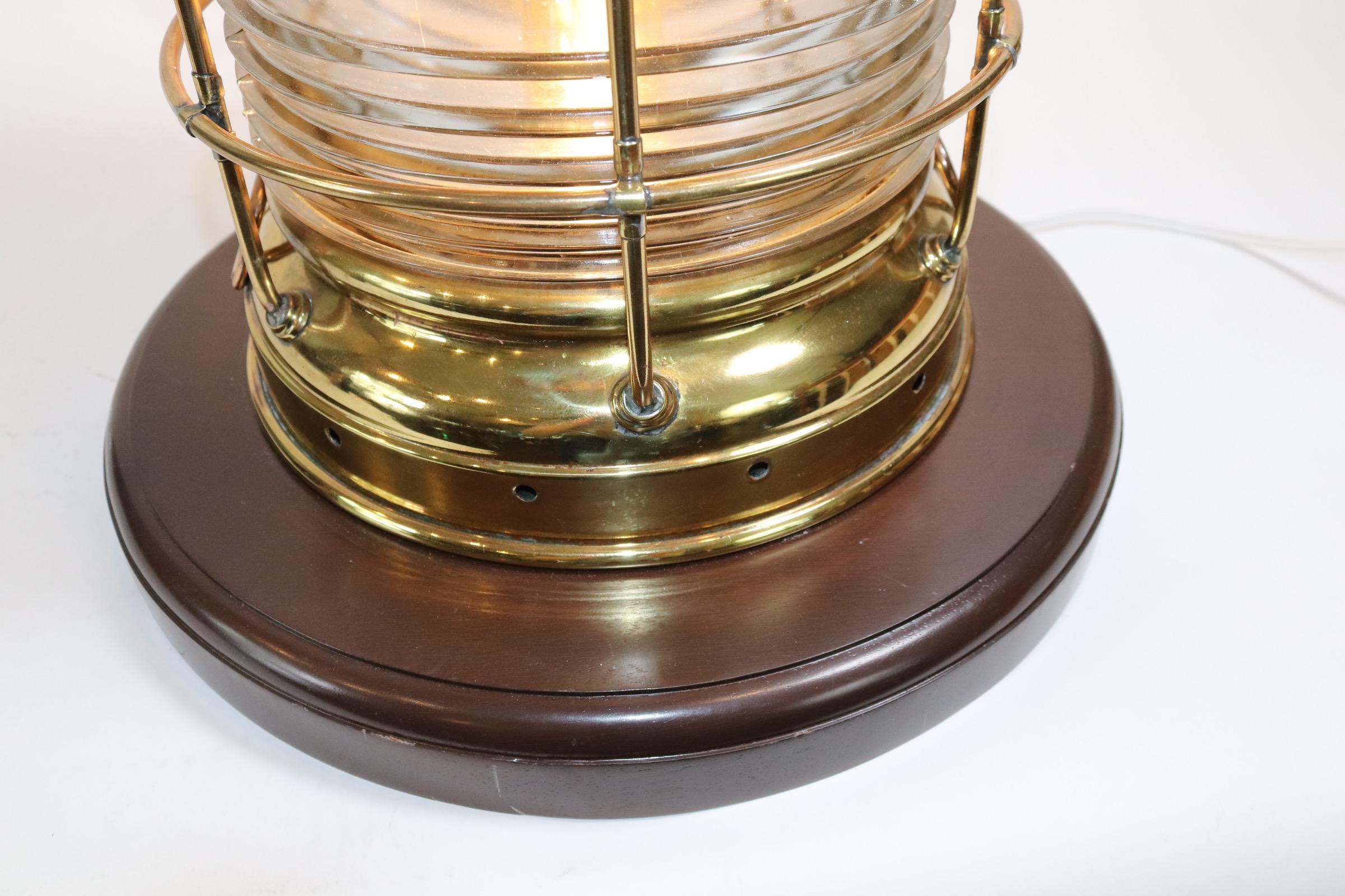 High quality highly polished and lacquered ships anchor lantern by Perko of Brooklyn New York. The thick Fresnel glass lens is mounted into the housing and surrounded by a protective brass cage. The lantern is mounted onto a thick wood base with