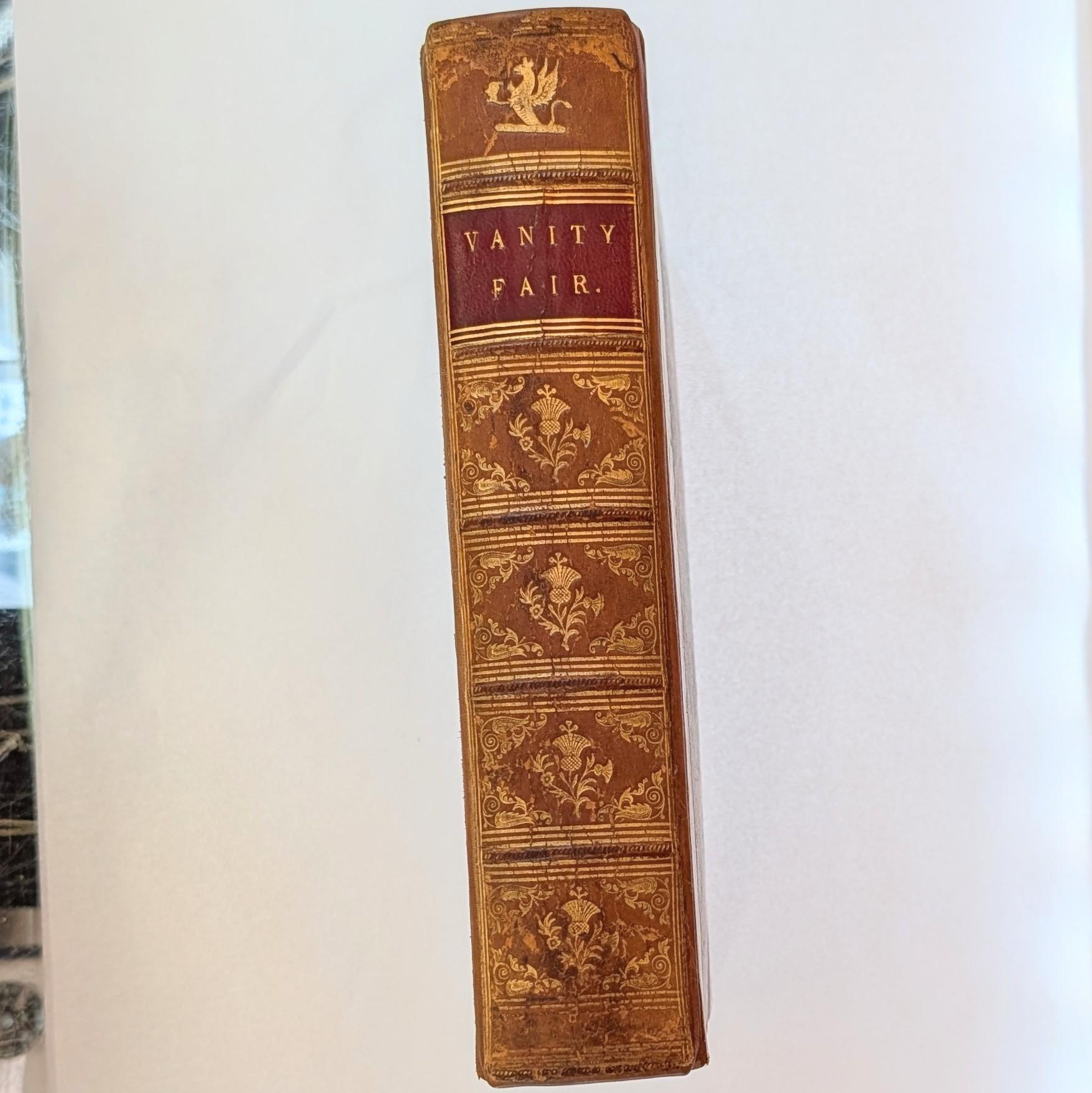 L'accessoire de bureau par excellence : Il s'agit d'une rare édition originale anglaise de Vanity Fair (1848), le chef-d'œuvre durable de William Makepeace Thackeray et l'une des pierres angulaires de la littérature anglaise du XIXe siècle.

Relié