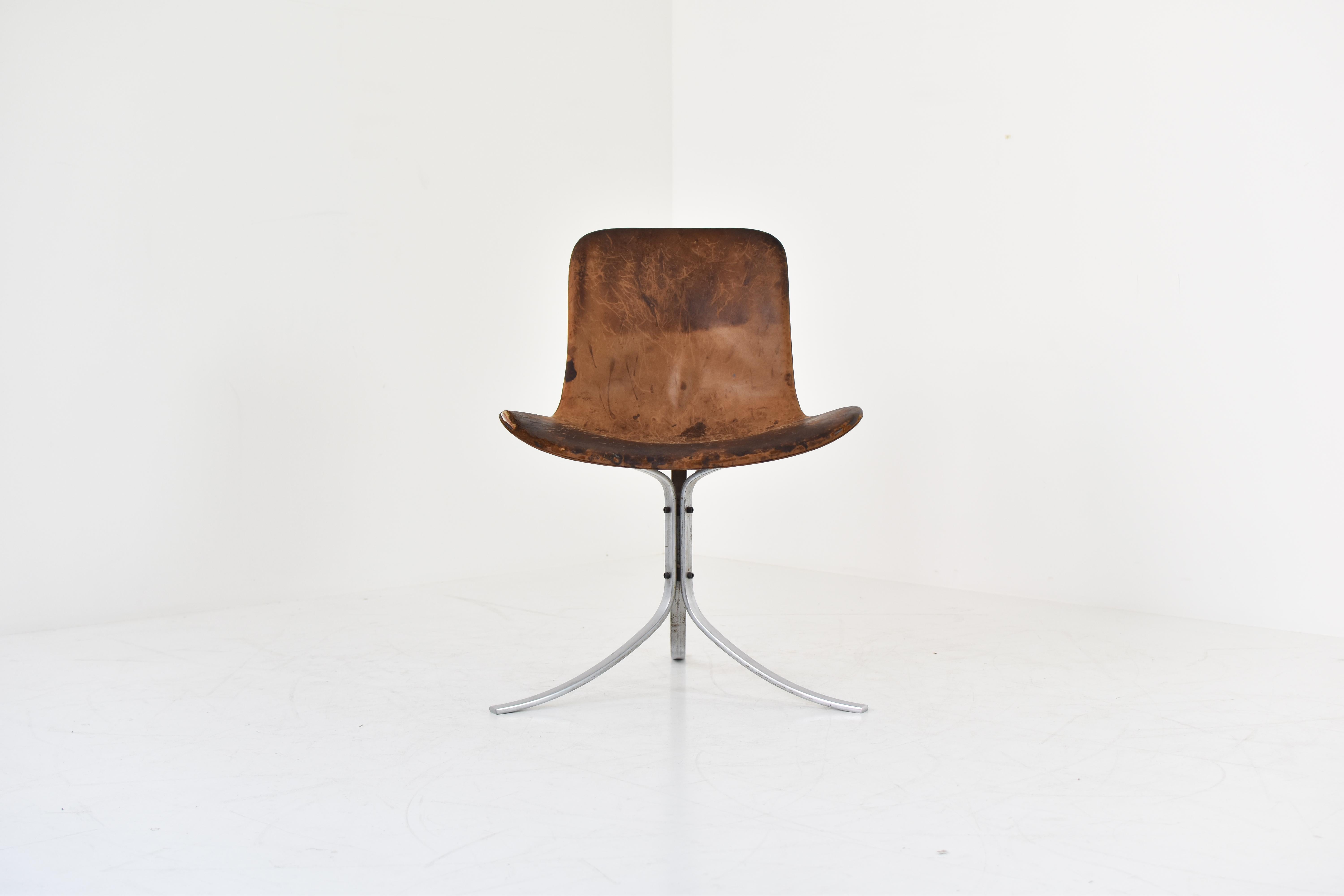 First edition PK9 tulip chair by Poul Kjaerholm for E. Kold Christensen, Denmark 1961. This chair features a flat steel frame and the original cognac leather upholstery. Superb patina with visible damage on the seating. Marked in the frame with the