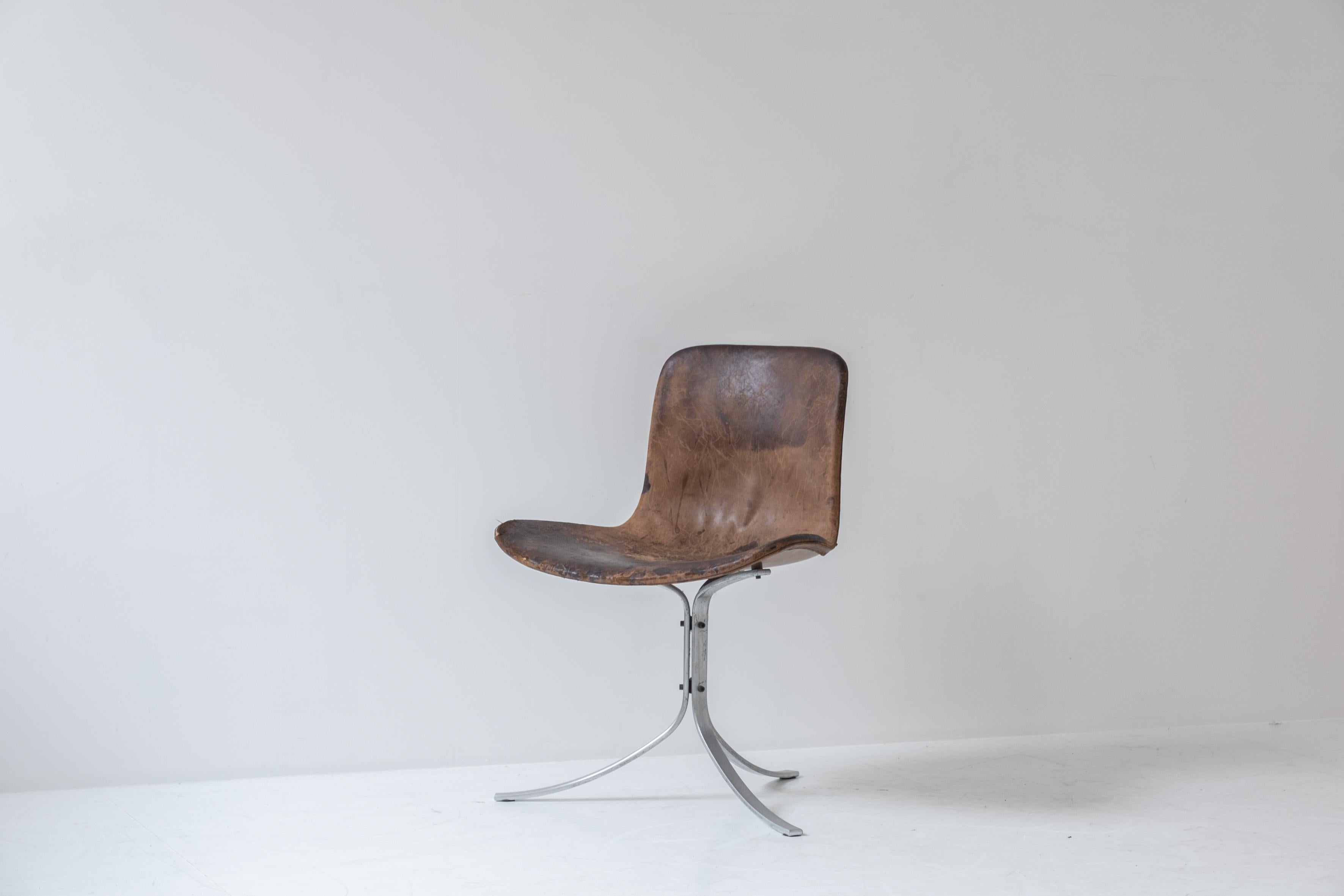 First edition PK9 tulip chair by Poul Kjaerholm for E. Kold Christensen, Denmark 1961. This chair features a flat steel frame and the original cognac leather upholstery. Superb patina with visible damage on the seating. Marked in the frame with the