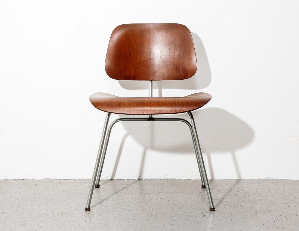 First generation DCM chair designed by Charles and Ray Eames for Herman Miller. Dark walnut molded plywood construction with chrome rod base.