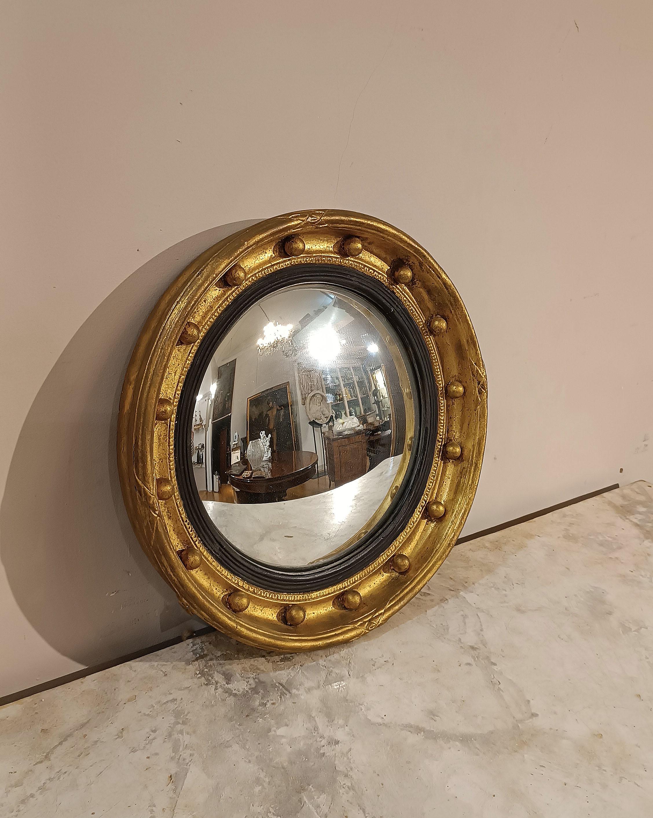 Elegant circular lens mirror from the Empire period. The mirror is characterized by its carved and gilt wooden frame, enriched with delicate decorative geometric engravings on all four sides, as well as a geometric decoration surrounding the mirror.
