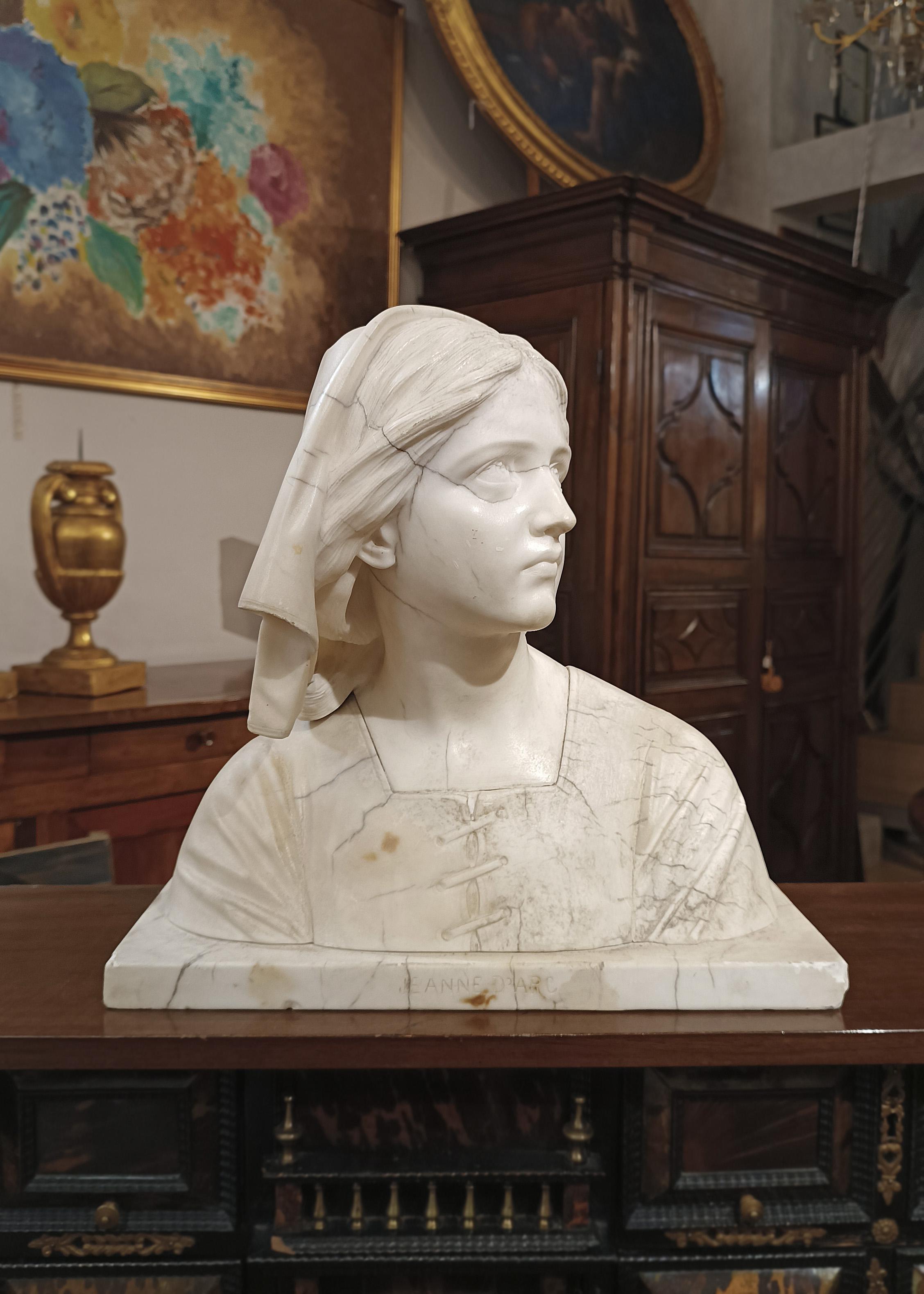 An extraordinary marble bust, characterized by greyish veins, depicting the Maid of Orléans, Joan of Arc. The attribution is confirmed by the inscription 