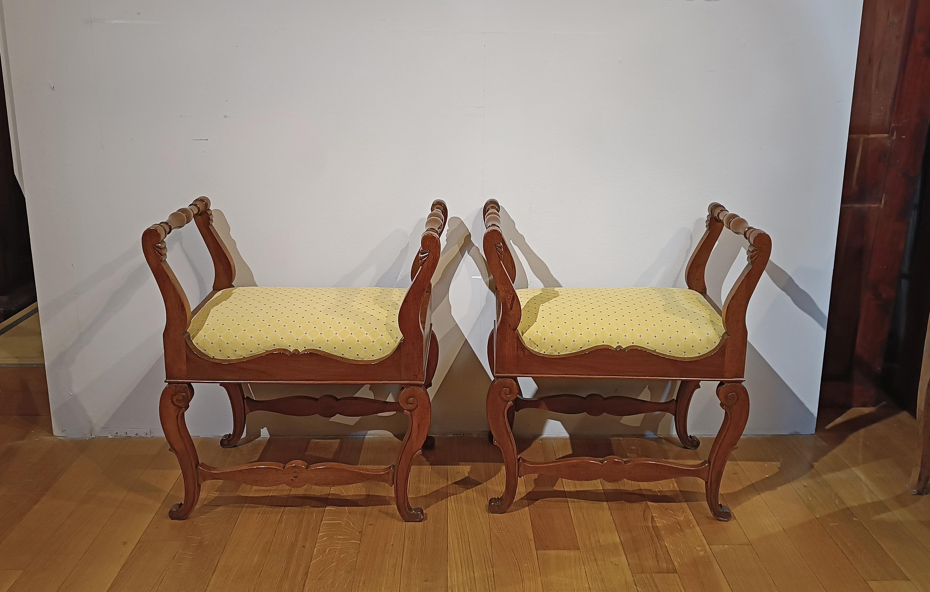 Elegant pair of hand-carved walnut stools. The stools feature curved legs decorated with geometric patterns and curls, while the outwardly curved armrests are molded, lending a touch of refinement. The very comfortable seat is upholstered in yellow