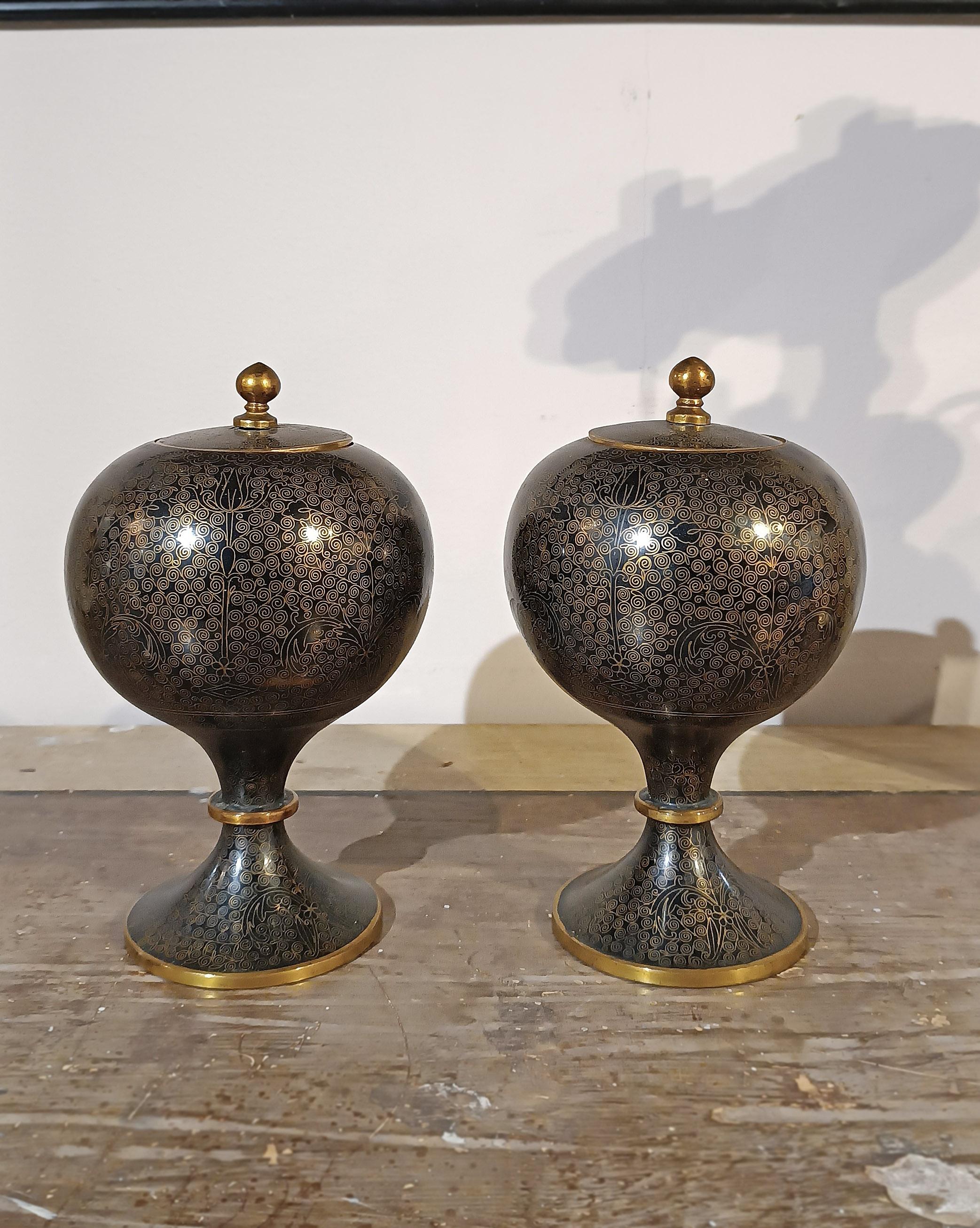 Paire de vases en forme d'urne raffinés, fabriqués selon la technique du cloisonné et finis en laiton poli. Les vases présentent une forme rare avec un corps globulaire, un pied annelé et un bouchon en métal. De couleur gris anthracite, elles sont