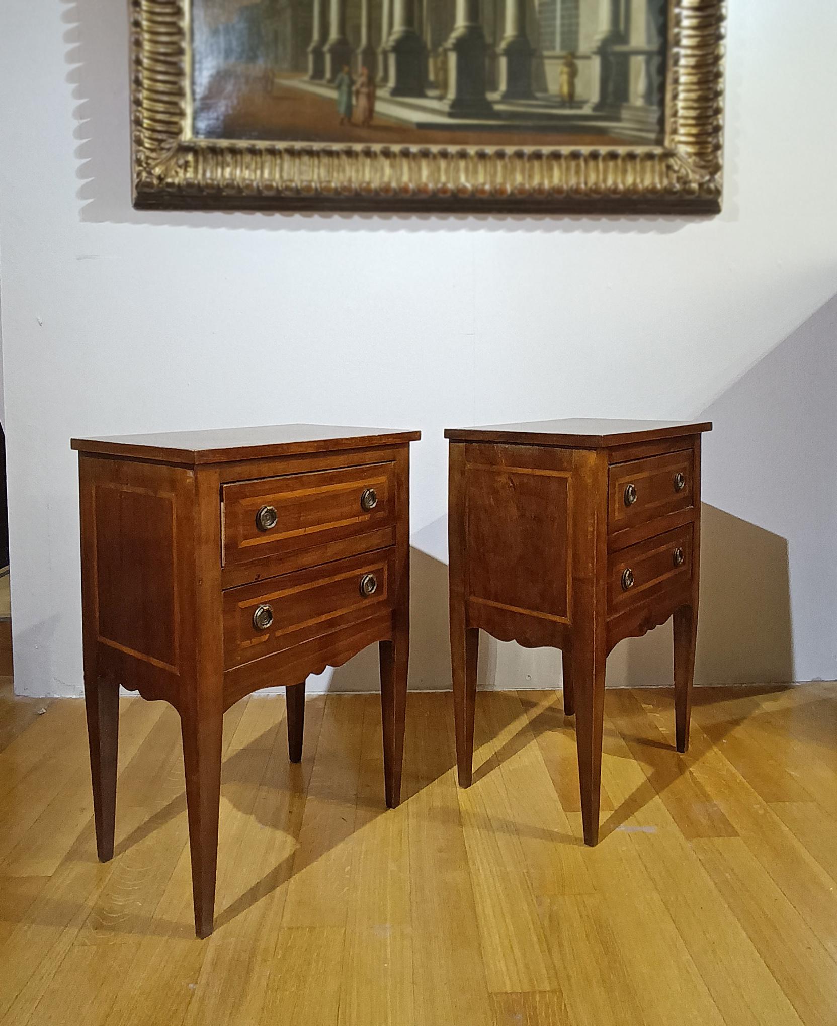 Élégante paire de tables de chevet en noyer massif, finement sculptées et enrichies d'incrustations en bois fruitier. Ces tables de chevet présentent un design linéaire avec des pieds pyramidaux tronqués. Leur structure est agrémentée