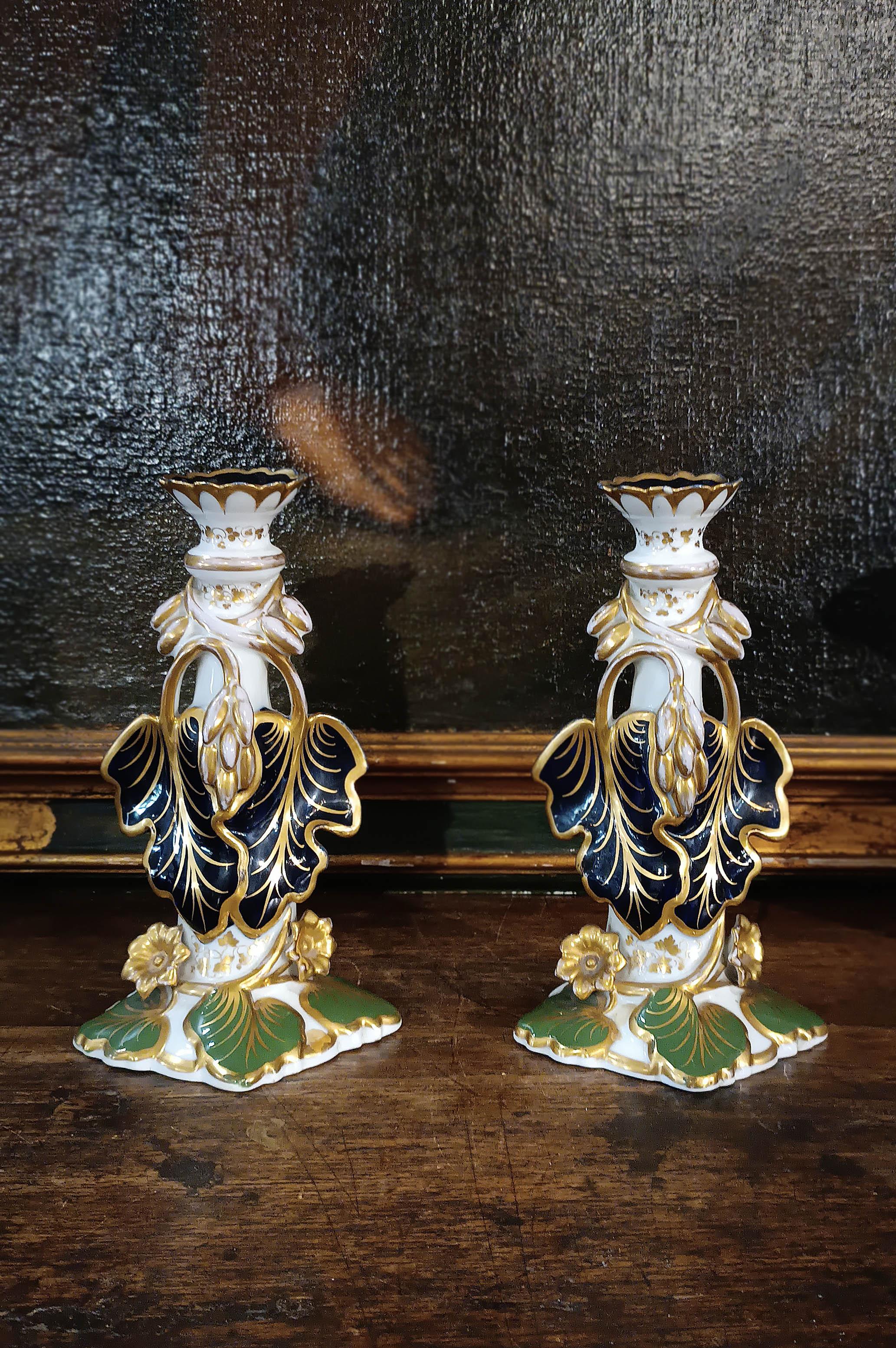 Elegant pair of single-light candlesticks in polychrome porcelain, perfect for illuminating any environment with style and refinement. The decoration of vine shoots and plant racemes in shades of blue and green, enriched with gold finishes, gives