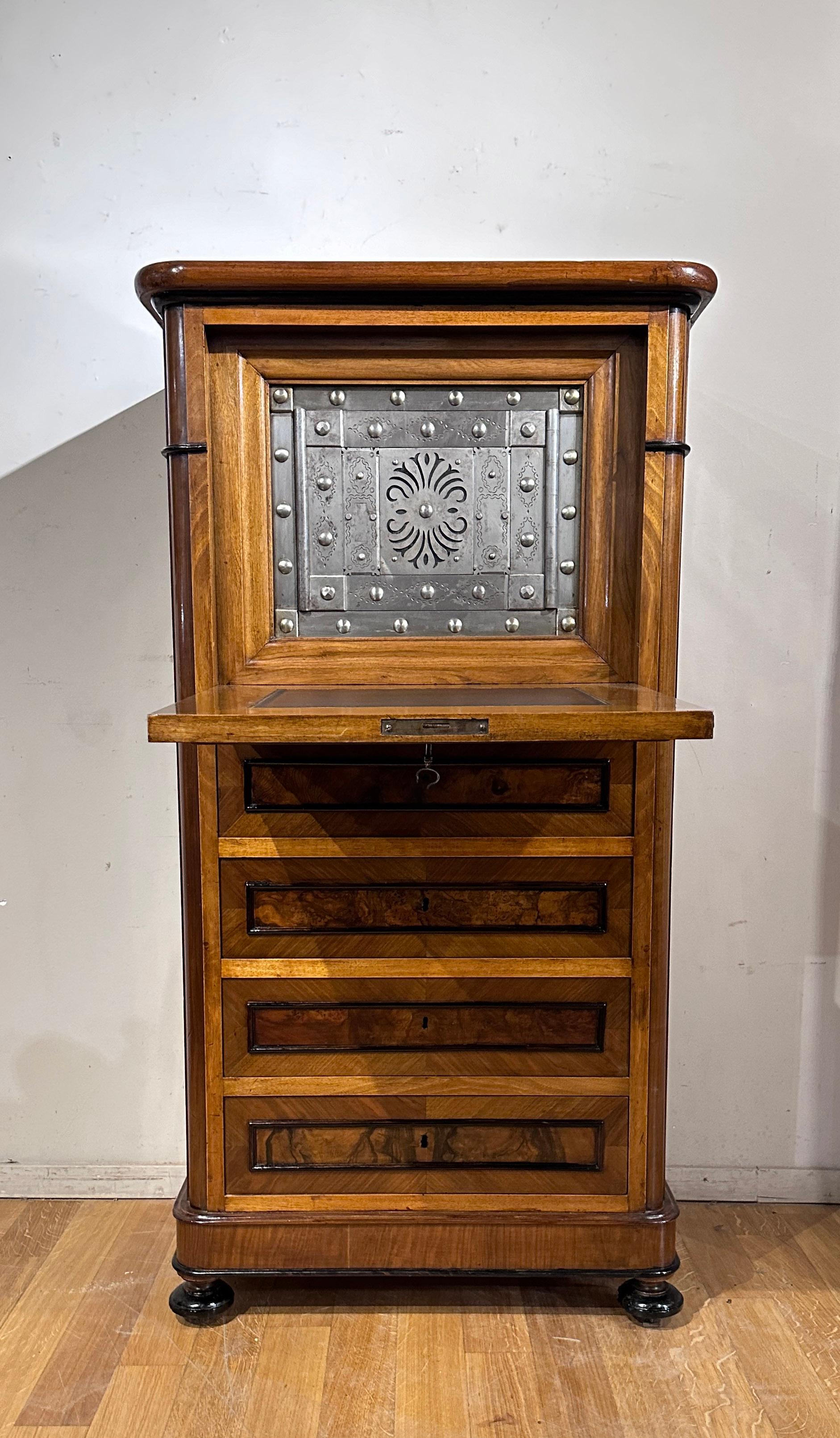 This burr walnut secrétaire is an elegant and distinctive piece of furniture, characterized by a linear design and onion-shaped feet. Its peculiarity lies in the presence of a safe hidden inside the folding top, covered in leather. The iron safe