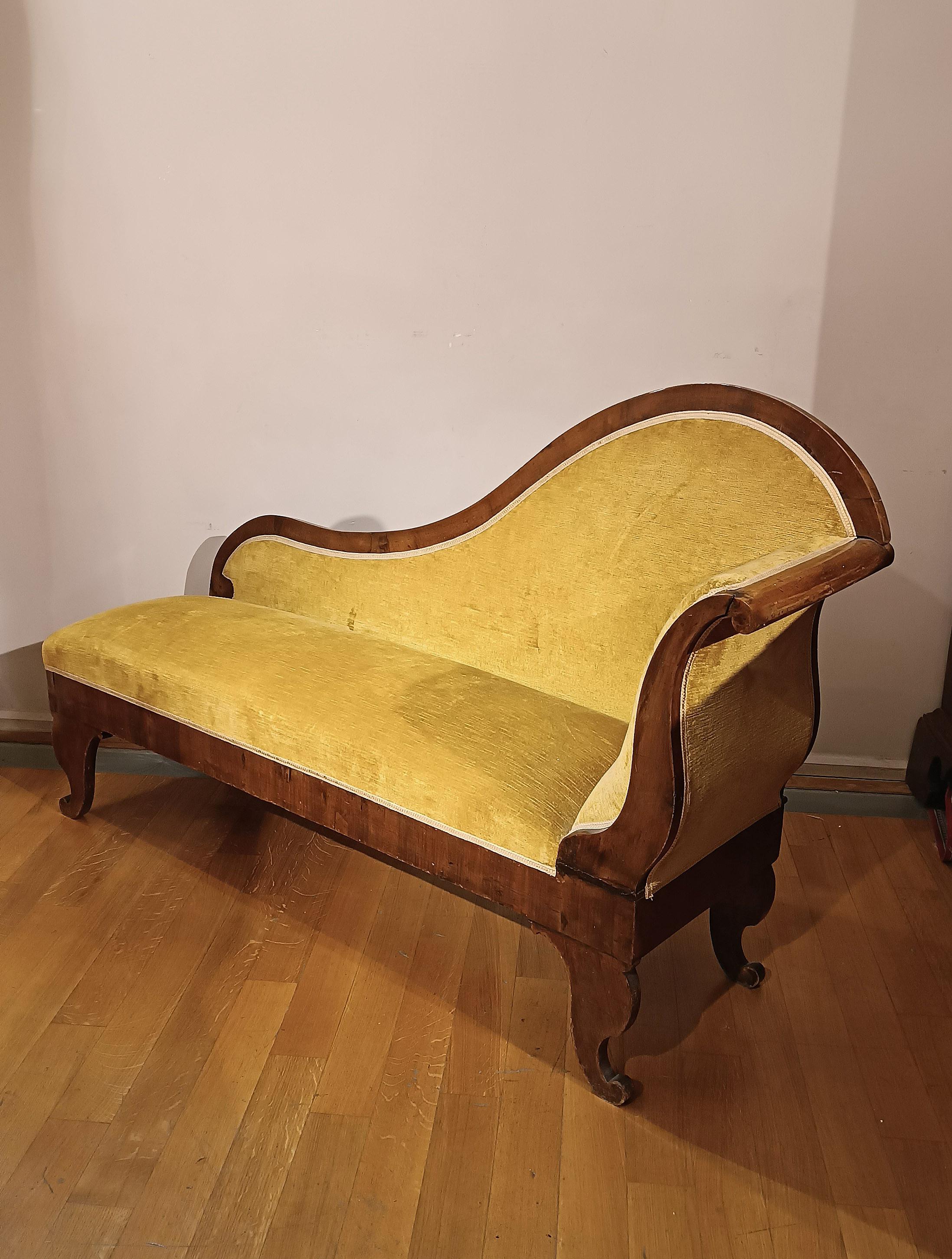 Petite et élégante chaise longue en noyer, tapissée de velours ocre en bon état. Les pieds, caractérisés par une élégante boucle qui rappelle la forme d'une corne d'abondance stylisée, apportent une touche distinctive. Comme le dossier, il présente