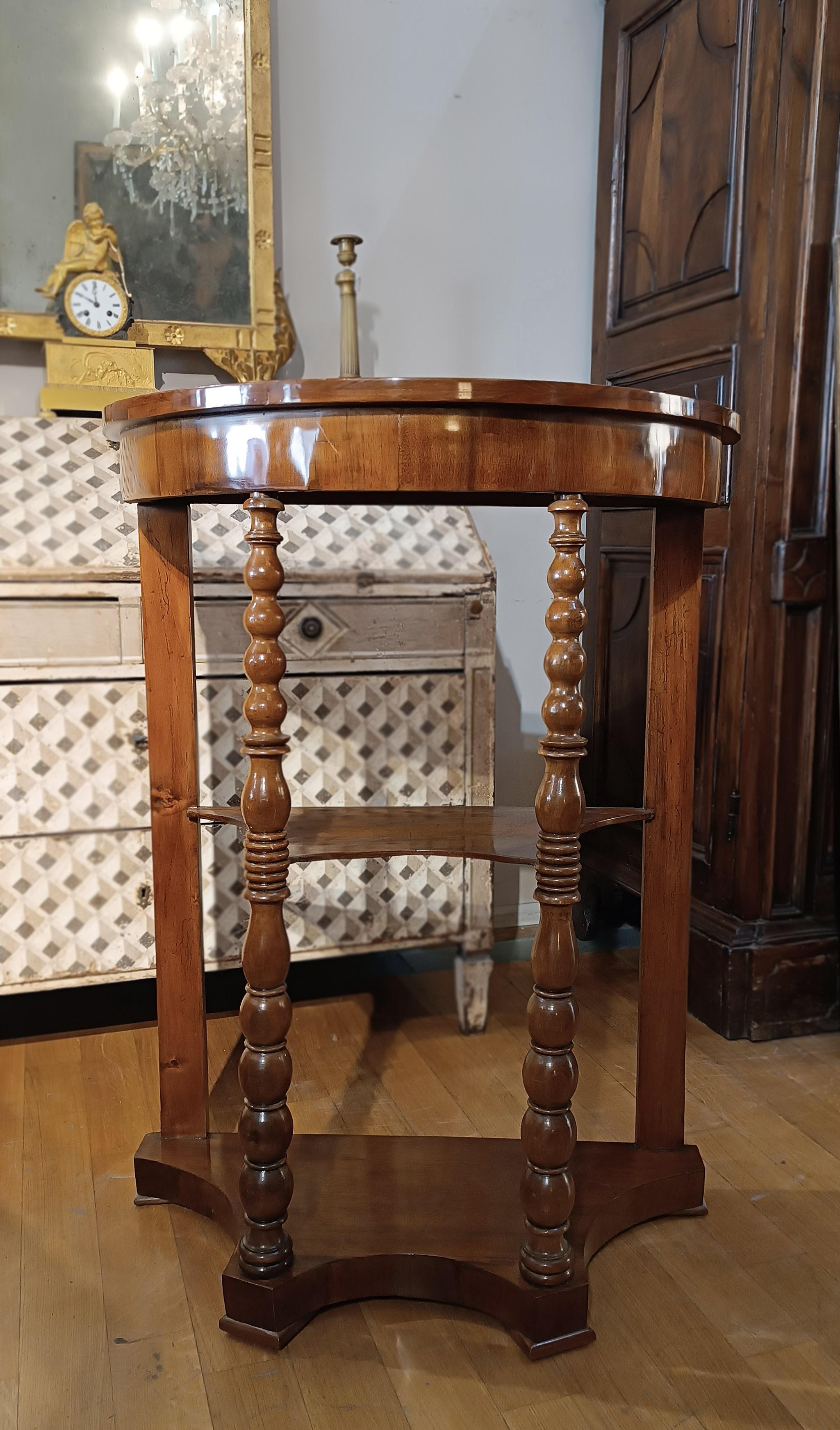 Elegant and refined étagère made of solid walnut wood and walnut veneer. The cabinet has a half-moon shape with three shelves, ideal for storing various types of objects. The decoration is finely finished and turned for the front shoulders, giving