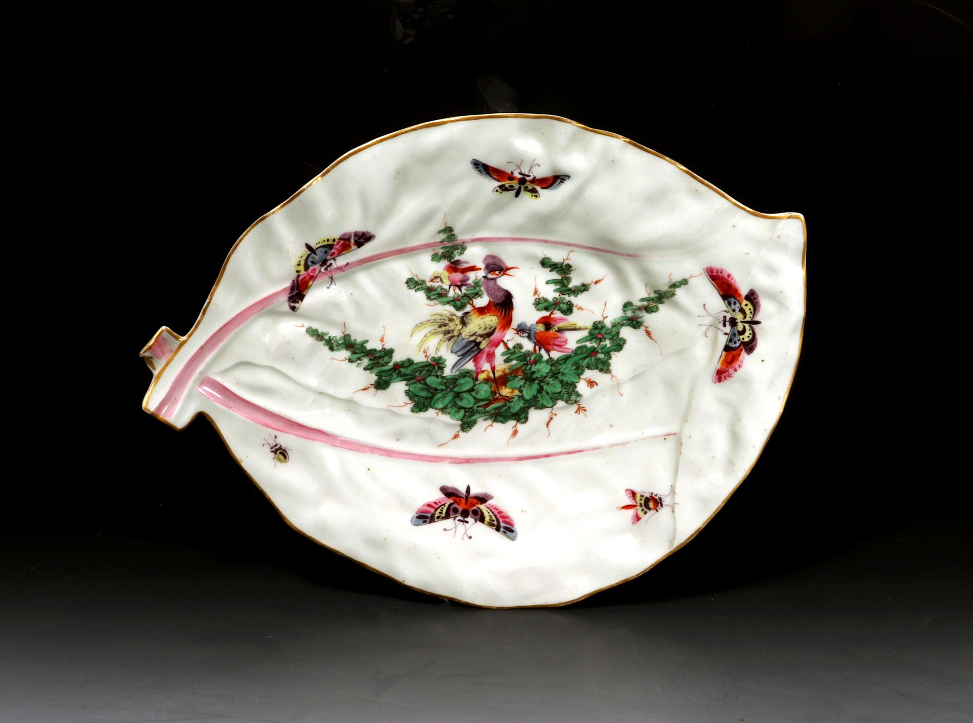 First Period Worcester porcelain fancy bird-decorated double-leaf dish,
Circa 1768

The Worcester porcelain molded dish is made in the form of two overlapping leaves. Across the painted center is a swag of green leaves with three exotic 