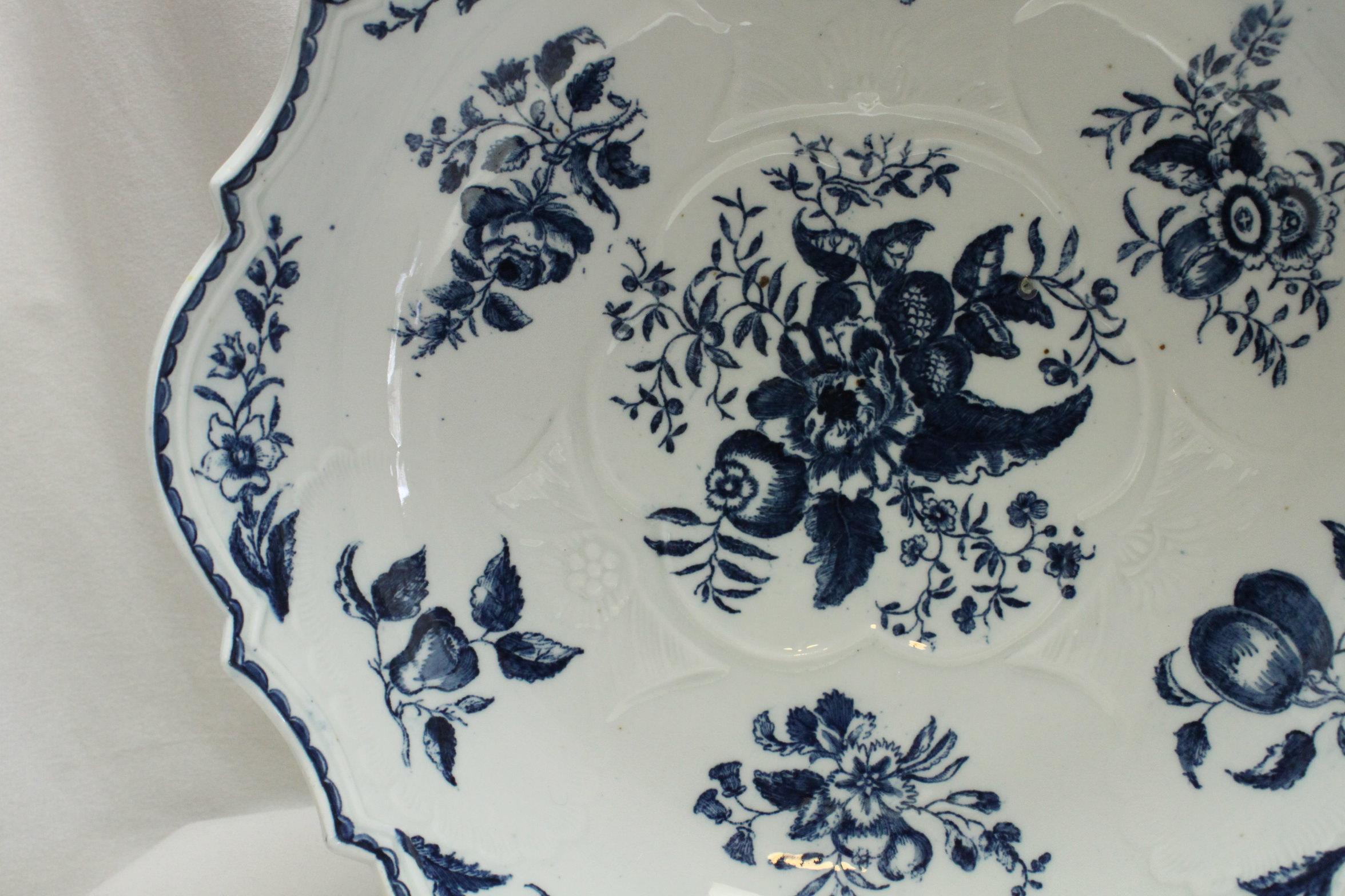This First period Worcester porcelain salad or junket bowl is decorated with the printed blue and white Pine Cone pattern. The central Pine Cone pattern is surrounded by prints of fruit and flowers. On the outside are prints of butterflies, fruit