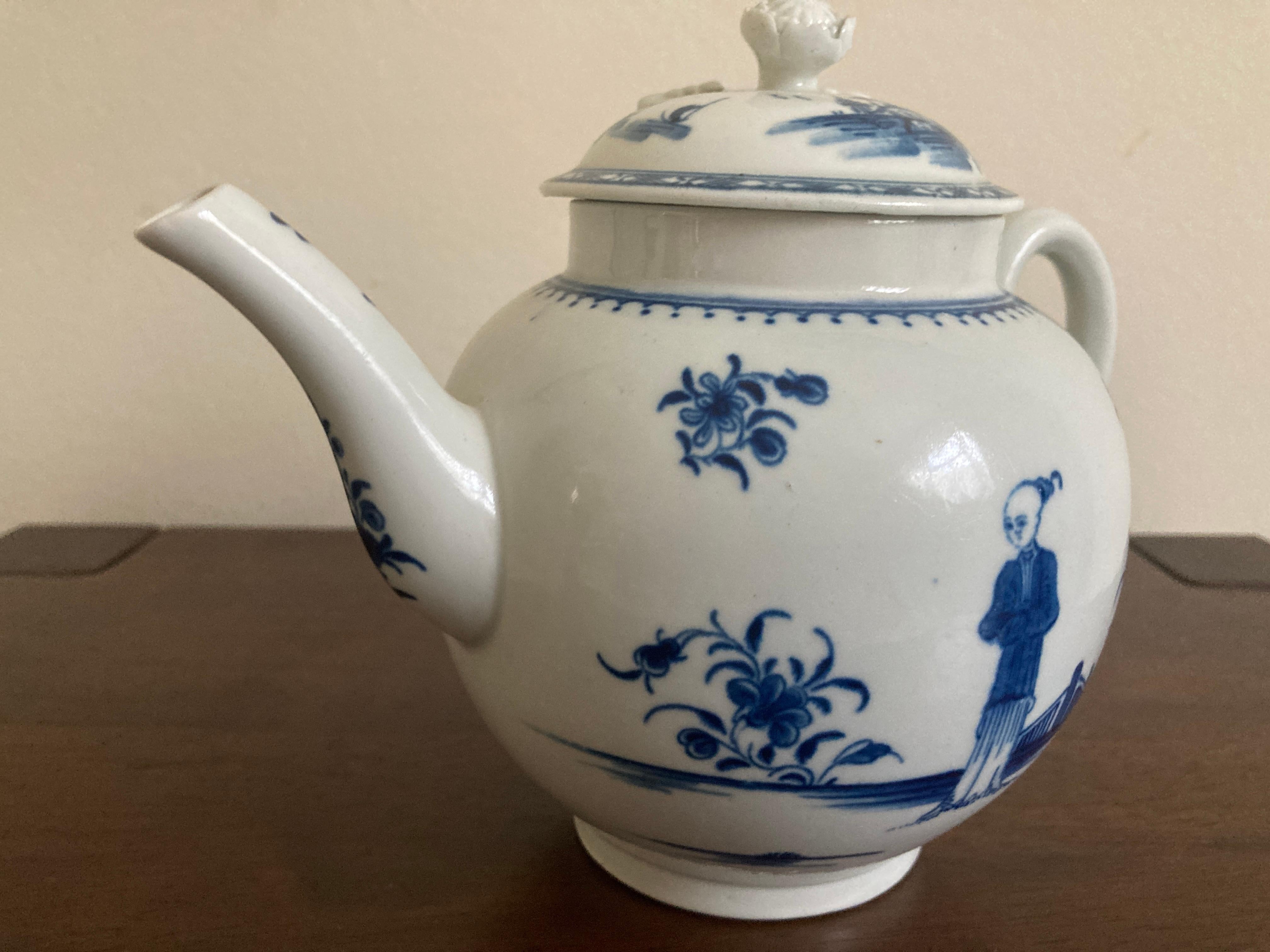 Worcester teapot, painted underglaze in ‘The Waiting Chinaman’ pattern, filled out with scattered sprays of flowers, the knop modelled as a flower. Blue crescent mark, c. 1770