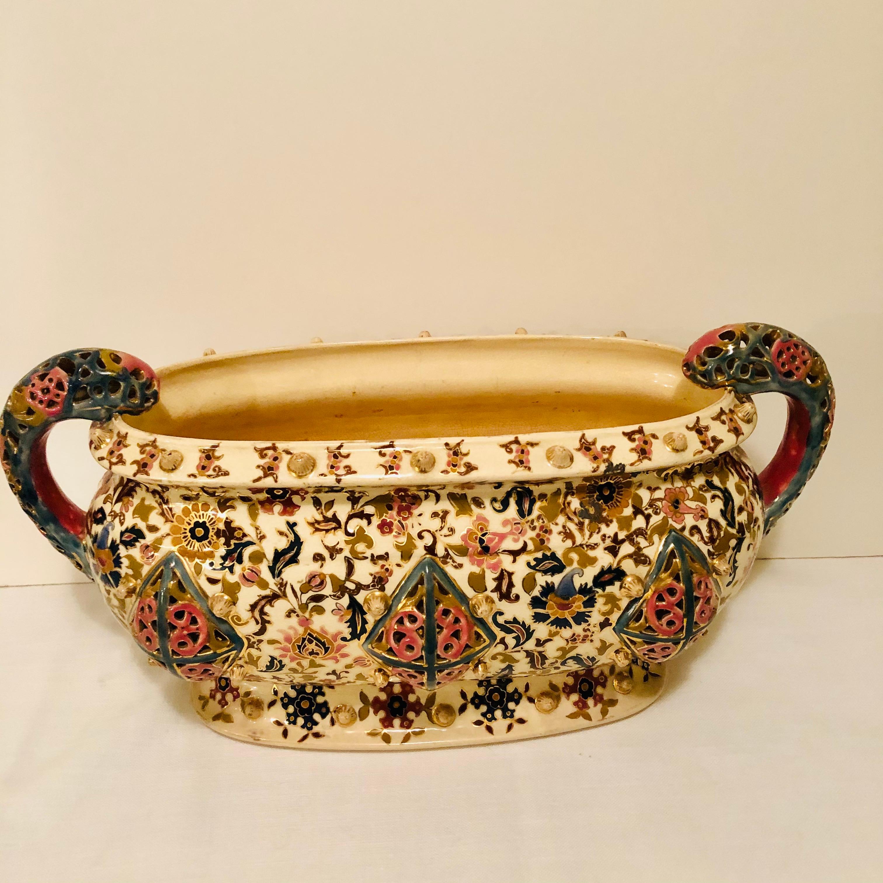 Very rare large Fischer Budapest centerpiece or jardinière painted with intricate bright colored decoration. It has reticulated colorful handles and three panels of reticulation with pink and green edges on the front and the back. It is very