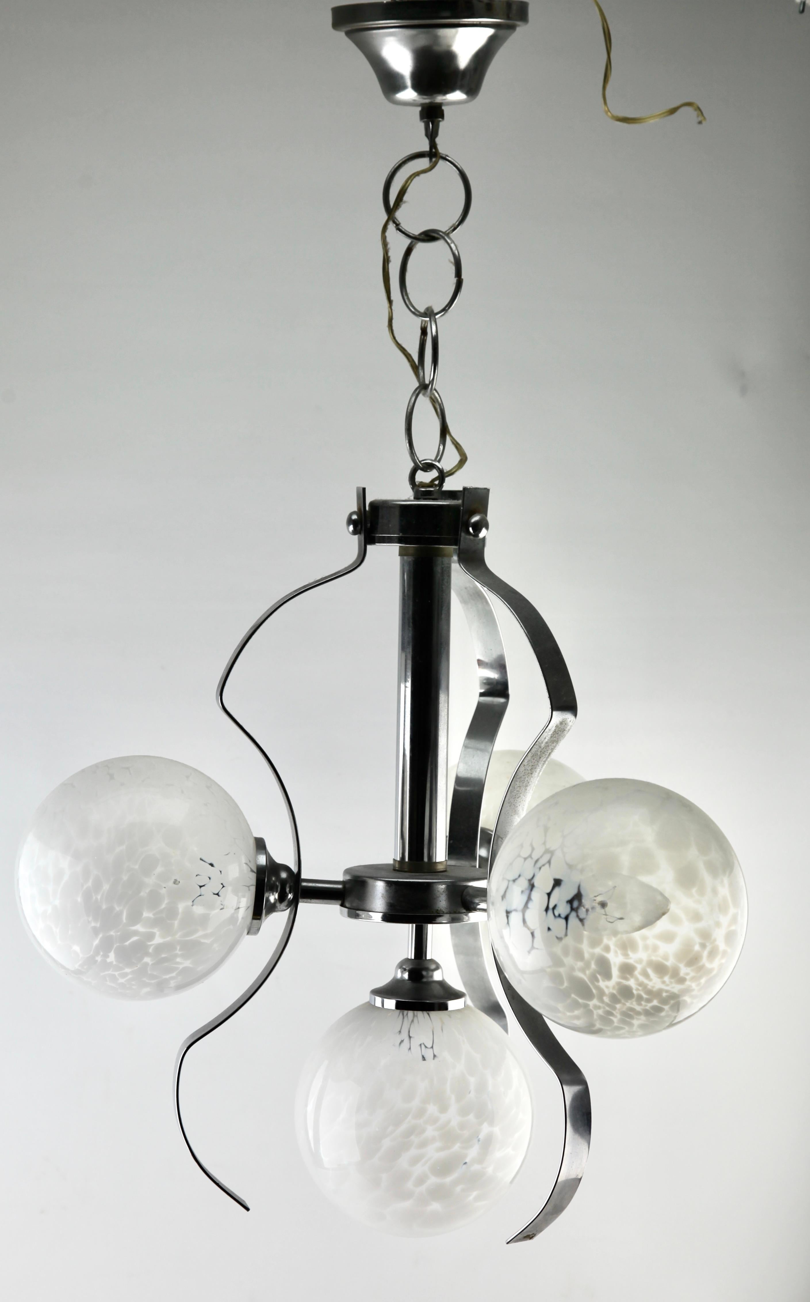 Issu de la gamme de la société Fischer Leuchten, ce centre d'éclairage comporte cinq lampes (disposées en deux paires) sur une tige centrale chromée. Chaque lampe est munie d'une armature sur une plaque chromée et d'un abat-jour rond et globulaire