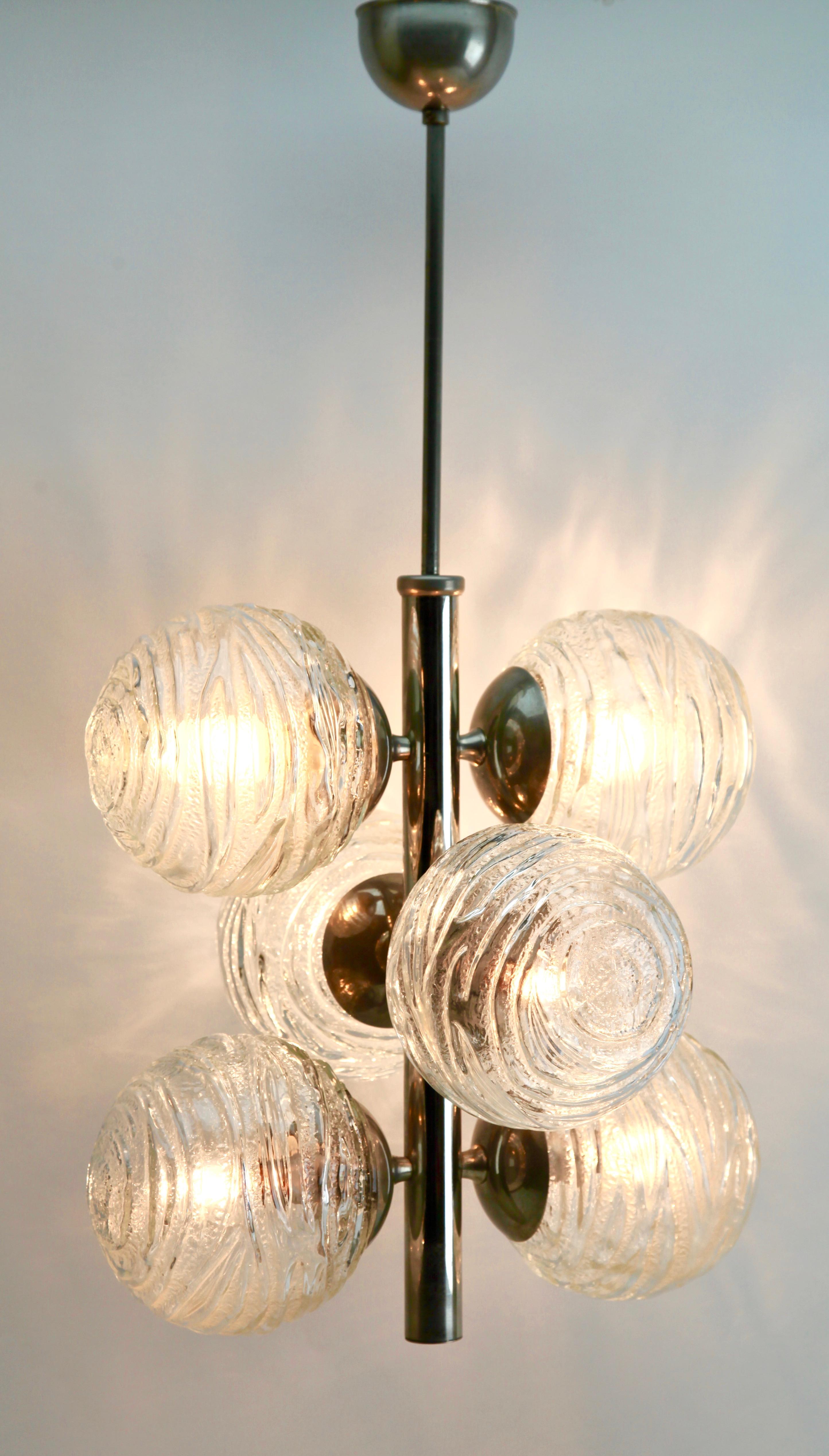 From the range by the Doria Leuchten Company, this center-light features six lamps arranged as three pairs) on a central chromed stem. Each lamp has a fitting on a chromed plate, and each holds a round globular shade of clear glass sculpted to