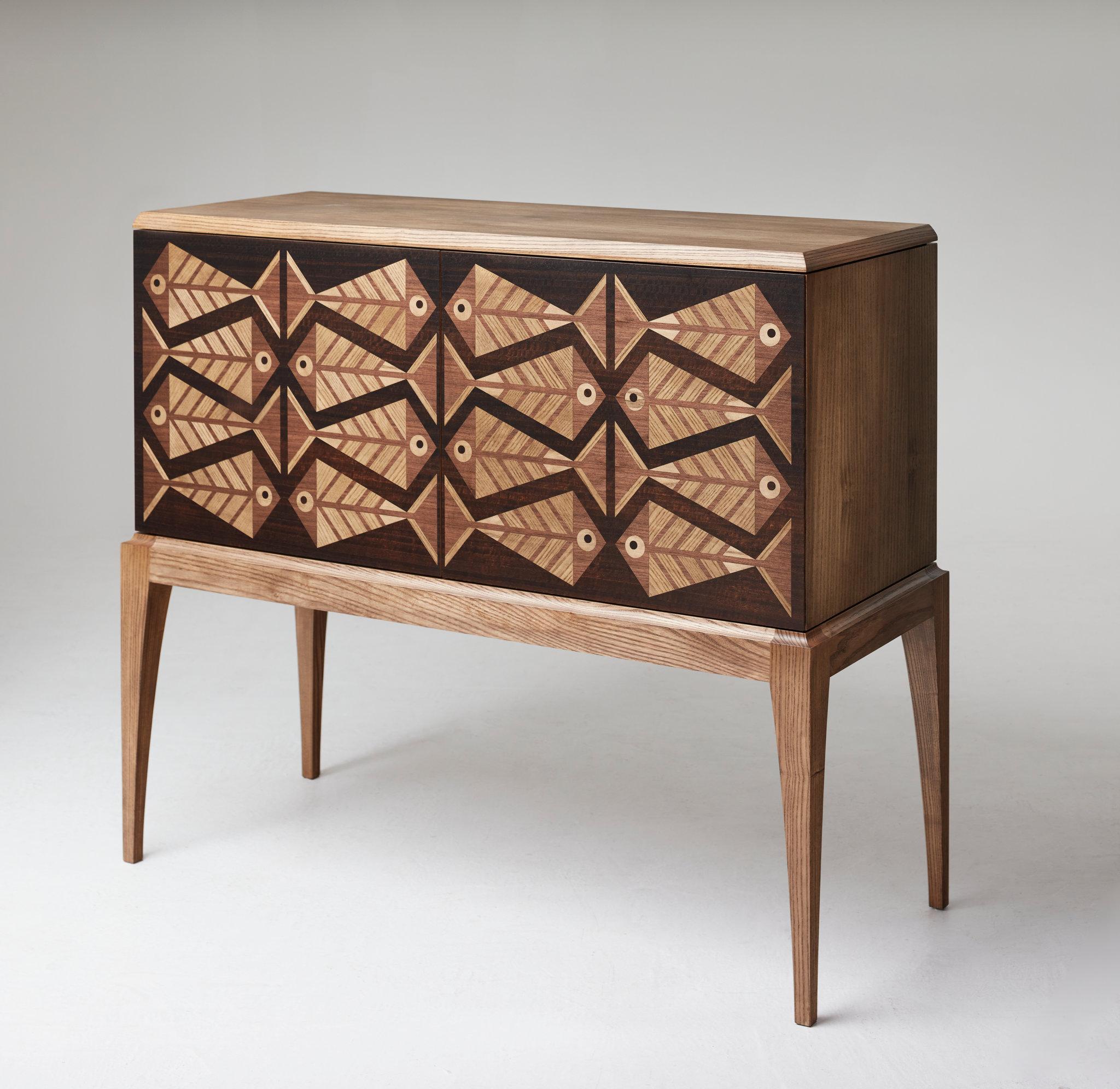 The intriguing aesthetic of this beautiful handmade cabinet is unique, unlike anything else you're likely to encounter.
The faces of the doors are decorated with wood-veneer marquetry in a geometric fish pattern using Walnut, Ash and Fumed