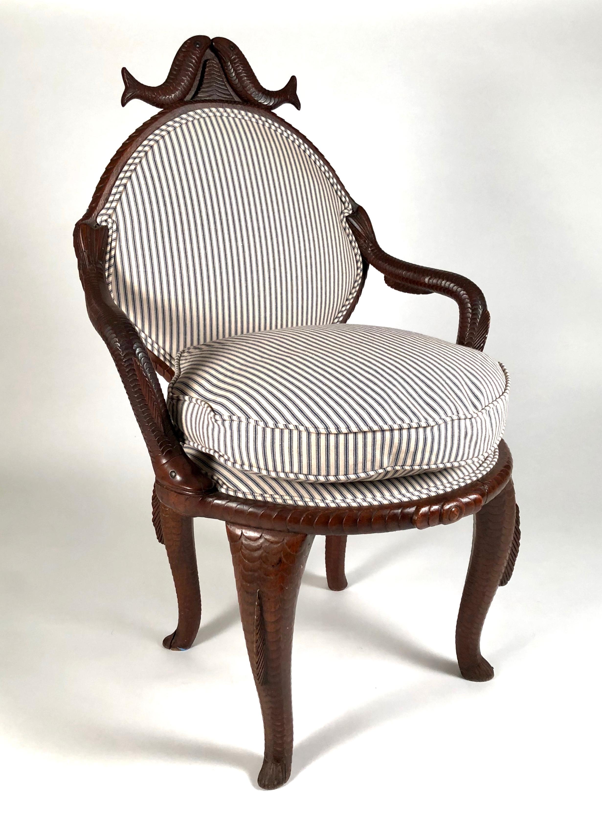 A highly unusual and beautifully made fish decorated 19th century American Folk Art hand carved mahogany open armchair with back, newly upholstered with blue and white striped ticking and down loose seat cushion. The cresting at the top of the back