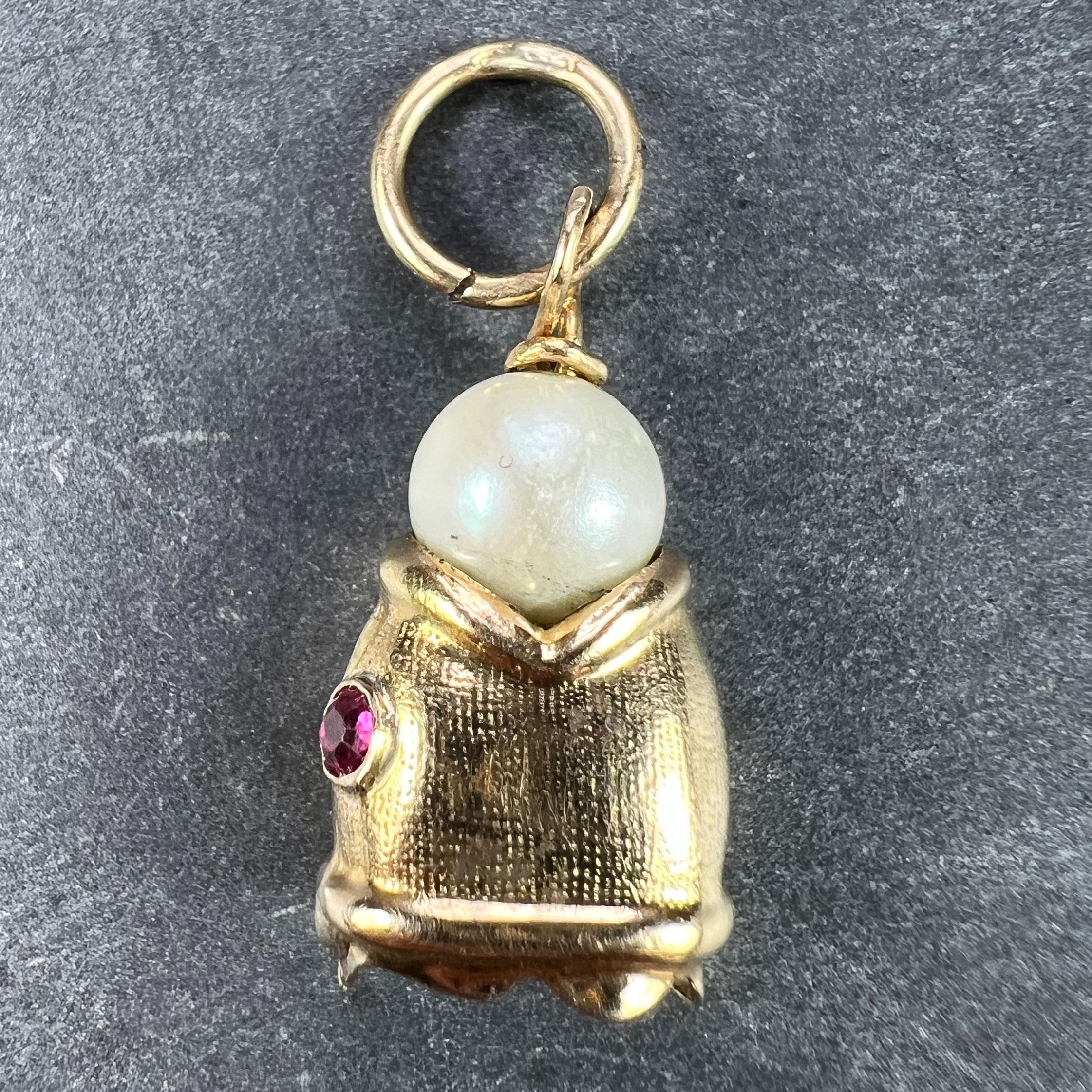 An 18 karat (18K) yellow gold charm pendant designed as a fish head with a cultured pearl in its mouth. Unmarked but tested for 18 karat gold.

Dimensions: 2 x 1.1 x 0.65 cm (not including jump ring)
Weight: 1.37 grams
(Chain not included)