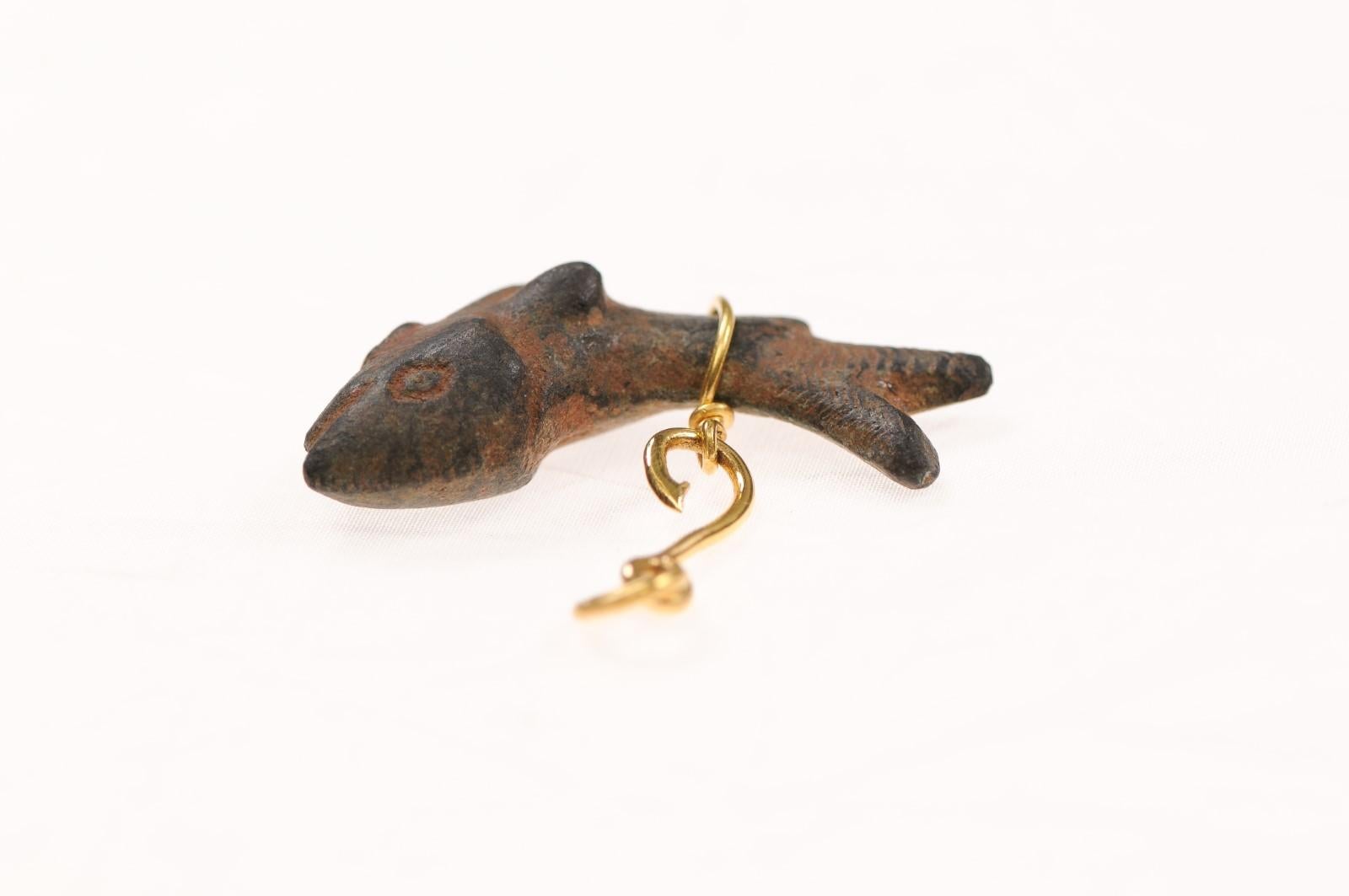 A charming bronze fish fashioned into a pendant with 21K gold. There is a marvelous patina that demonstrates the fish's age, and wonderful scale markings, as well as a small maritime inspired hook to hold the relic. This from the 1st to 3rd Century
