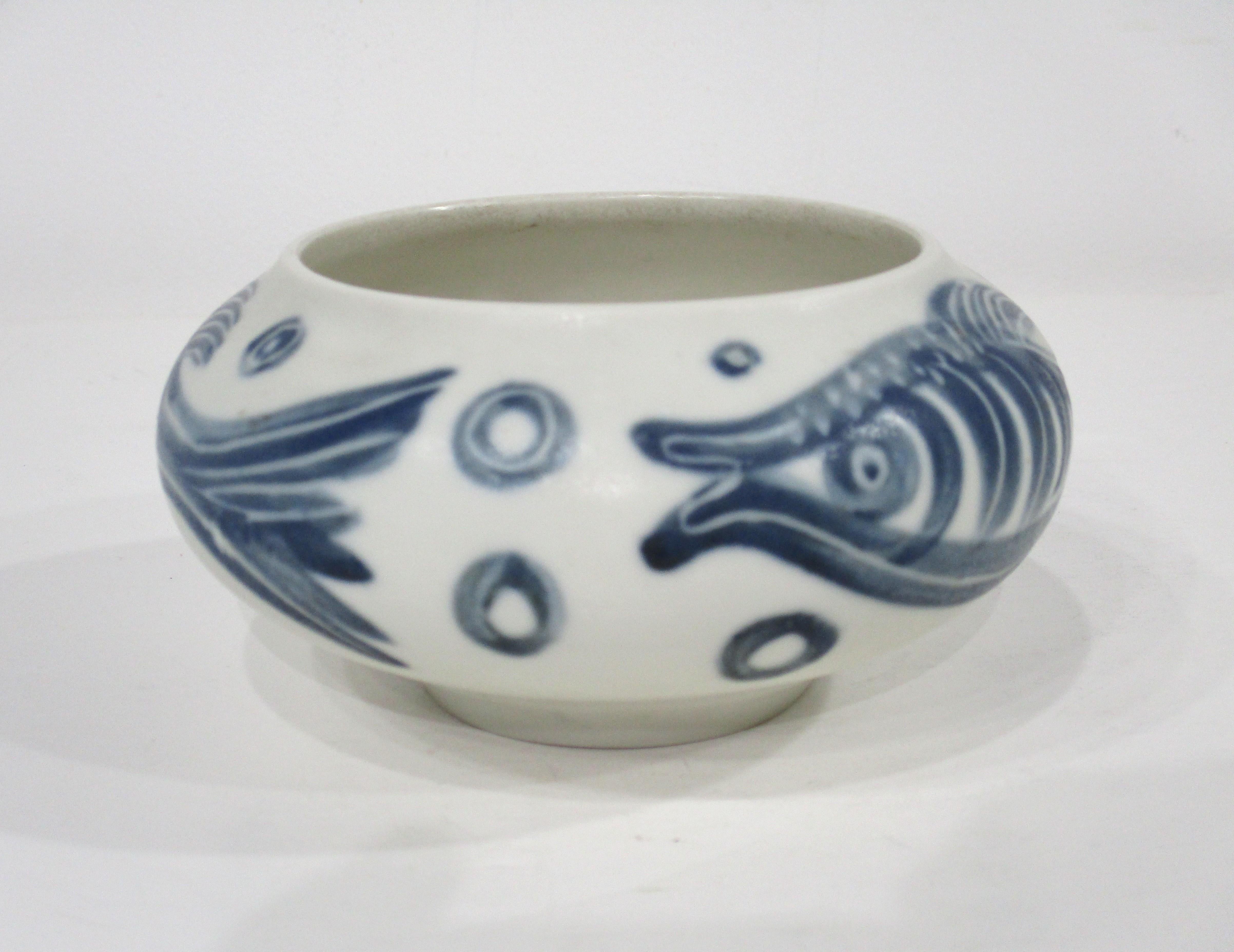 A beautifully handcrafted cream toned pottery stoneware bowl with ocean blue fish and bubble designs by artist Carl Harry Stalhane . The blue glaze on the body of the bowl gives the fish a floating and deep dreamy affect from the hand of head