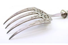 Fish serving fork in cut silver with grooves along the handle and four prongs