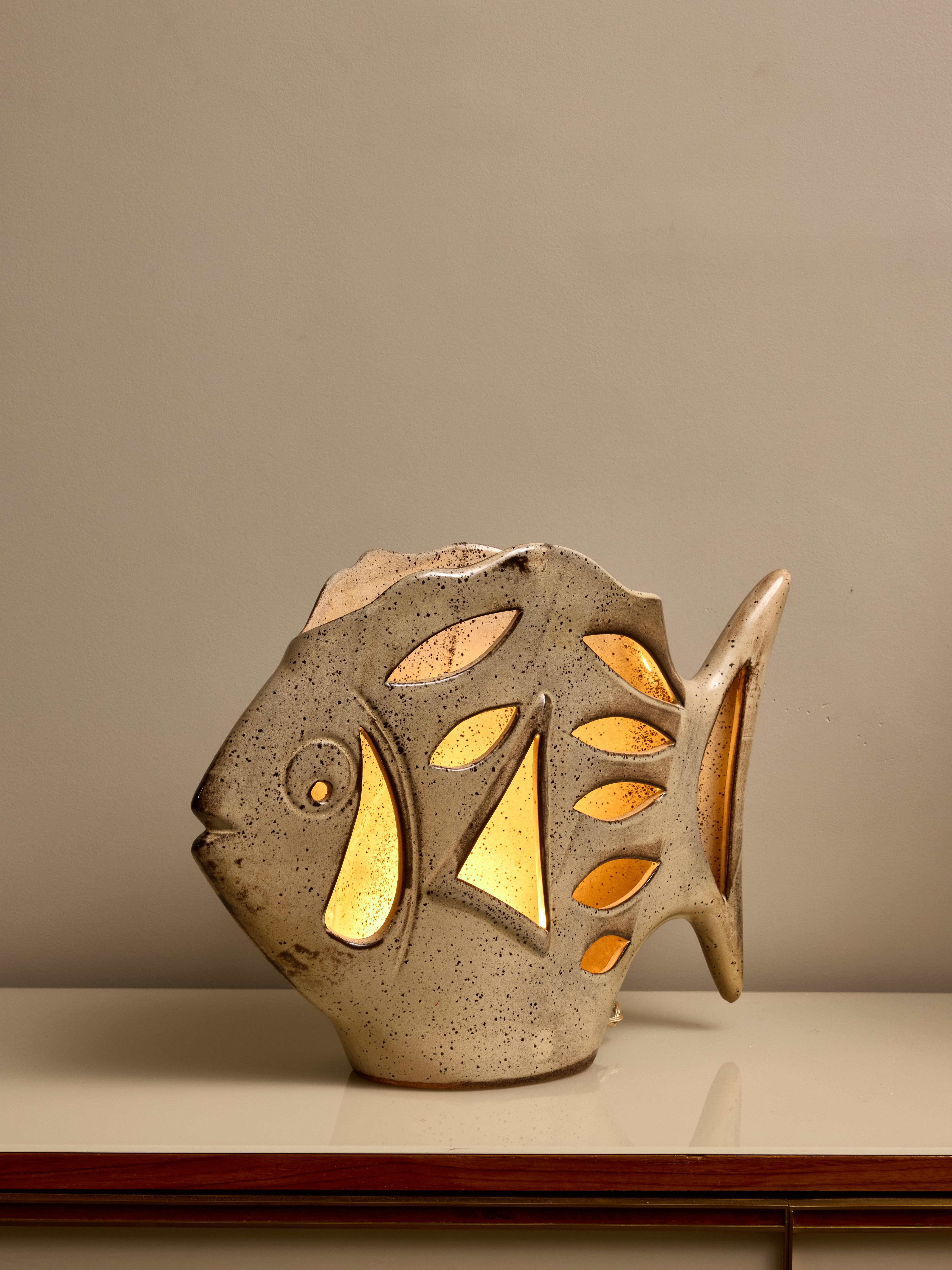 Lampe de table française en céramique émaillée, en forme de poisson. Il héberge une seule source lumineuse.

Fabriqué par l'atelier 