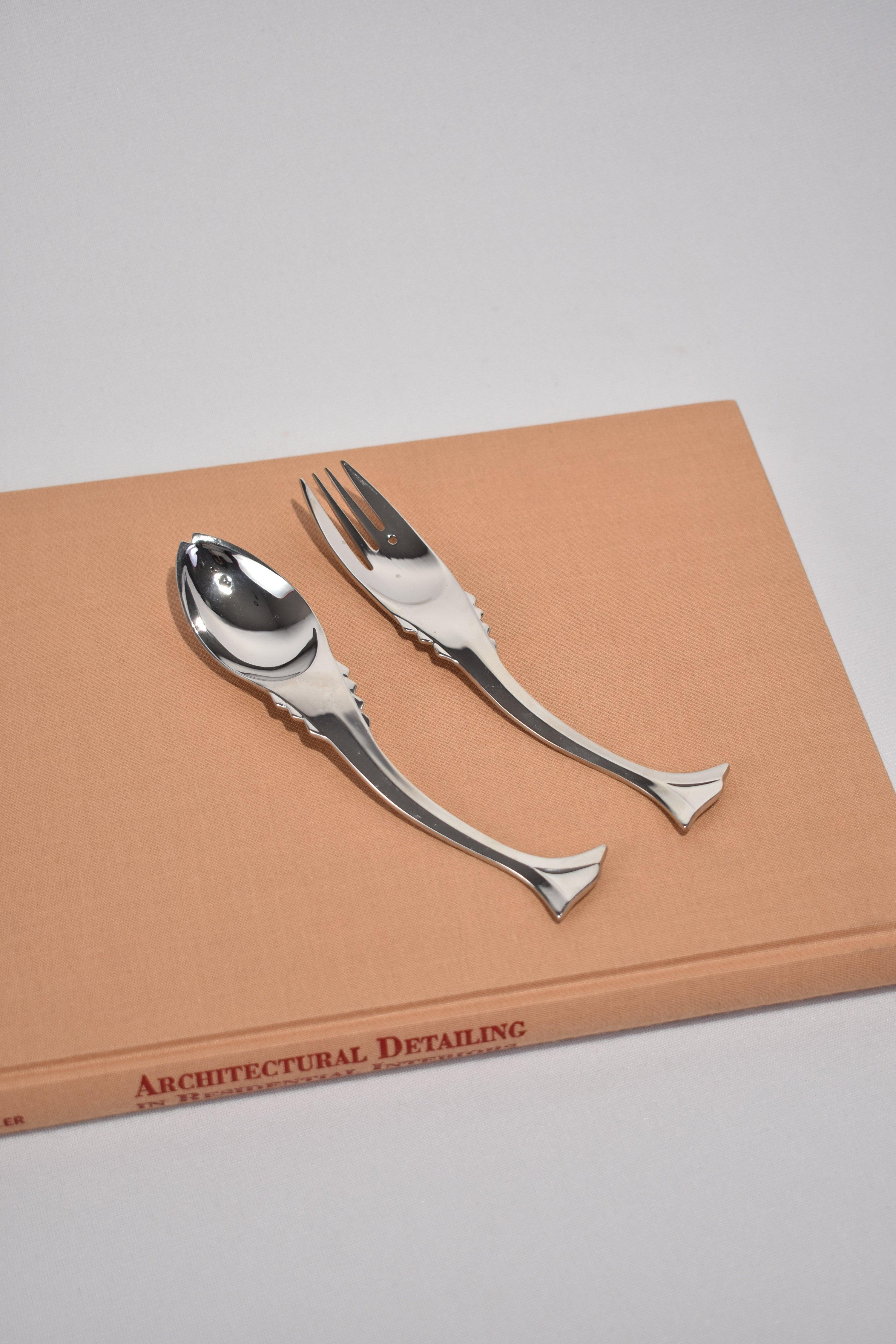 Vintage, stainless steel flatware set in abstract fish shapes. By Ricci Argentieri. Purchase includes one set of five pieces.

Dimensions: 
Knife, 9 in. long (22.86cm)
Spoon, 7.5 in. long (19.05cm)
Fork, 7.5 in. long (19.05cm)
Spoon, 6.5 in.