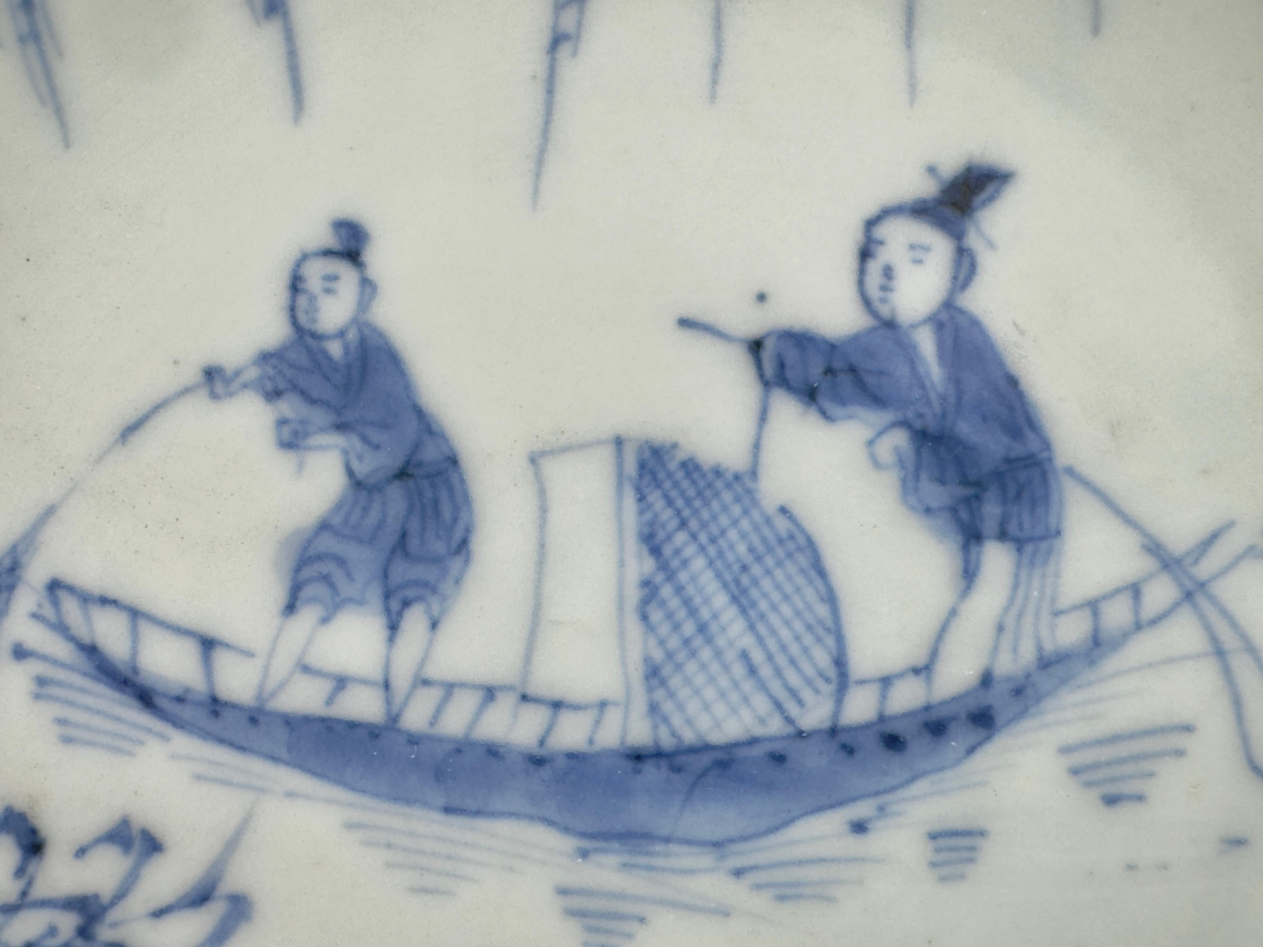 Ein Boot mit zwei darauf stehenden Figuren, die scheinbar mit einem Netz fischen. Unterhalb des Bootes, am Ufer, befinden sich zwei weitere Figuren, die einer anderen Tätigkeit nachgehen, möglicherweise dem Kochen oder der Zubereitung von Speisen.