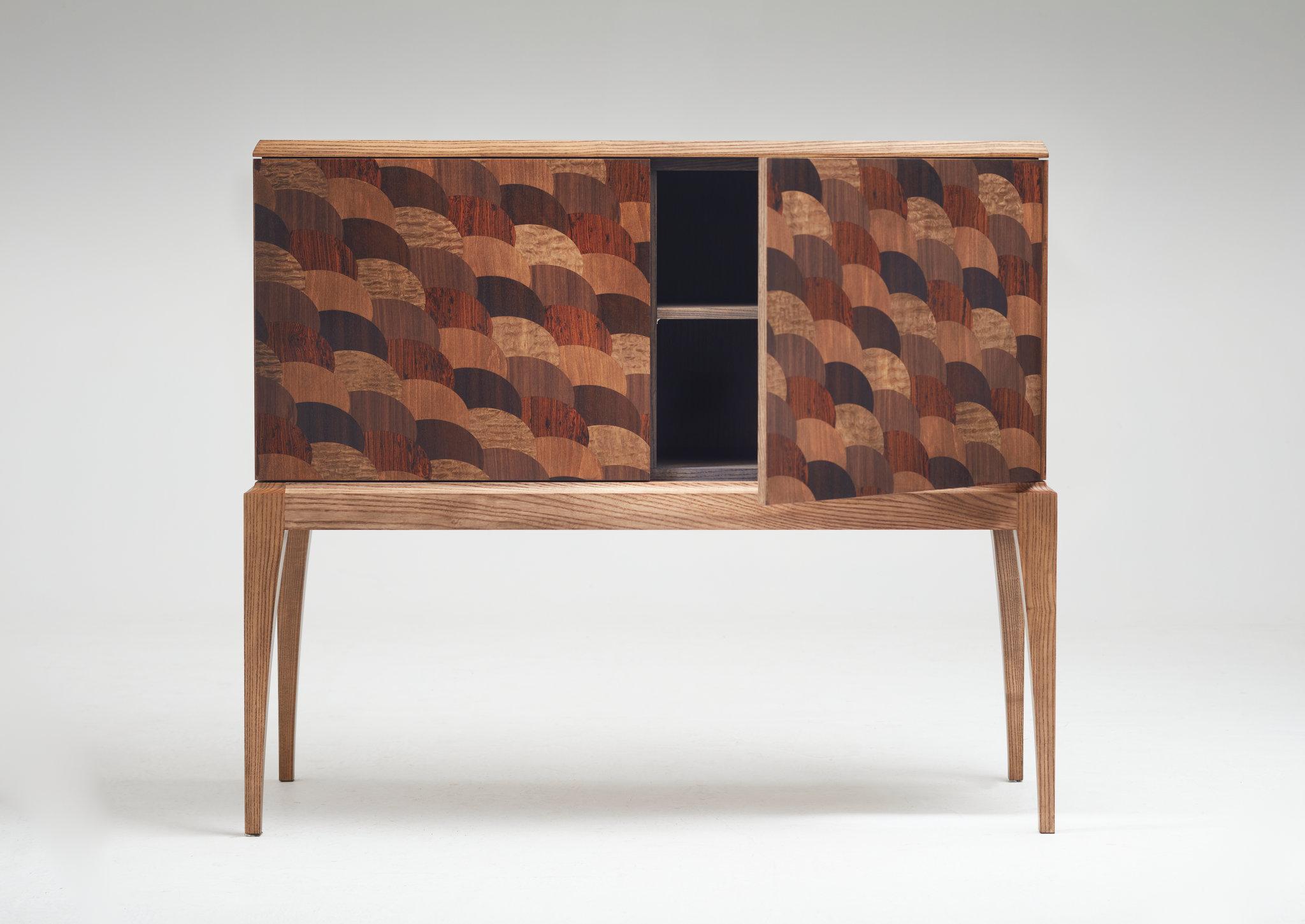 The intriguing aesthetic of this beautiful handmade cabinet is unique, unlike anything else you're likely to encounter.  The faces of the doors are decorated in wood-veneer marquetry in a modified  five- colour fishscale pattern which is based