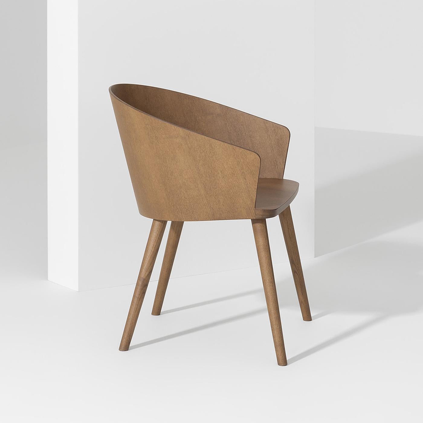 Elegant in its simplicity, this exquisite chair is entirely fashioned of solid ash wood boasting a tobacco brown finish. Designed by Victor Carrasco, its ergonomic yet welcoming seat with back and embracing armrests is inspired by the classic