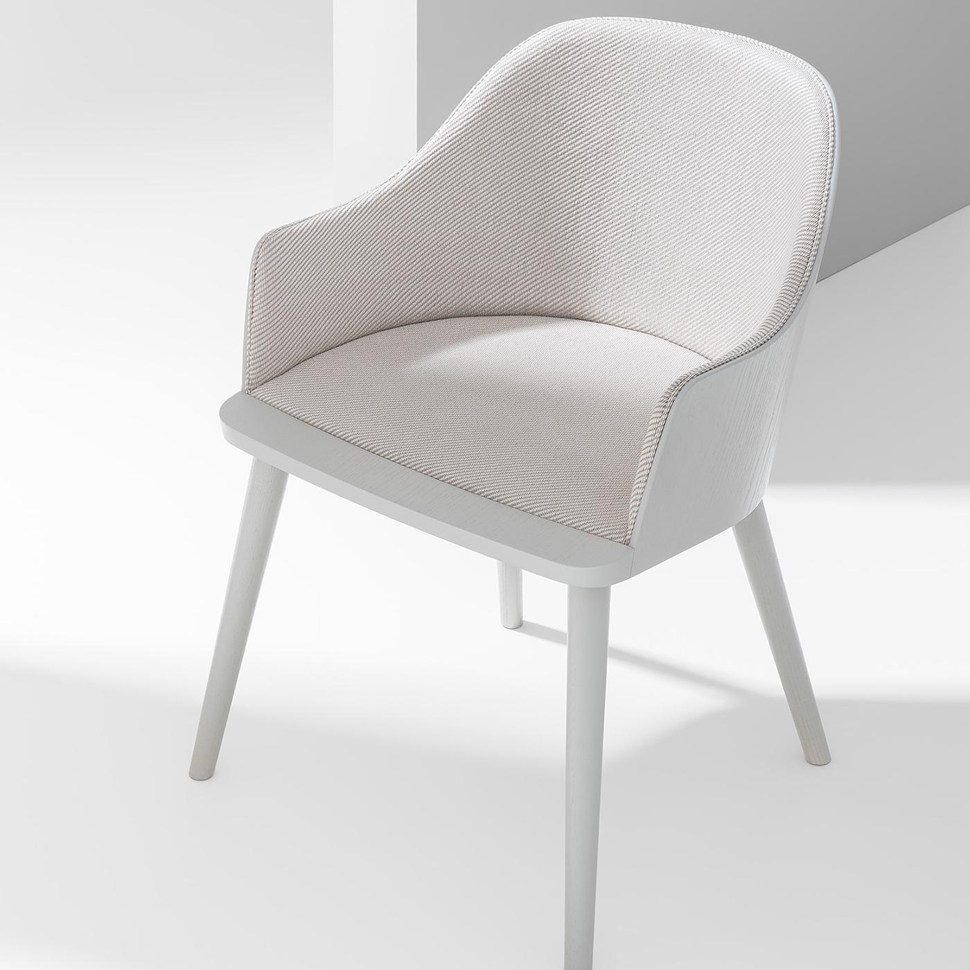 Elegant and refined, this chair is an ergonomic design by Victor Carrasco. Inspired by the classic silhouette of a shell chair, it features a large seat with curved back and embracing armrests, and rests on four slanted legs enriched with