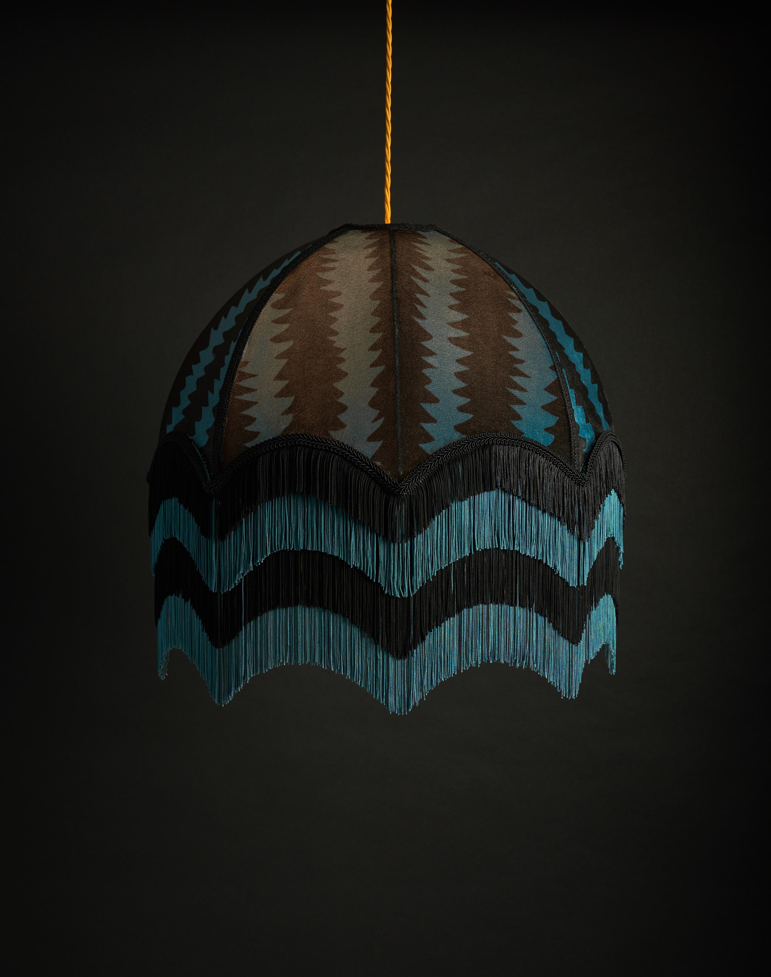 Fitz is a lively design in simple black and teal zigzag stripes, painted by Anna. The movement in this design enhances the ‘Jazz Age’ quality of this beautiful lampshade, as do the four layers of decadent, alternating fringe.

Anna Hayman lampshades
