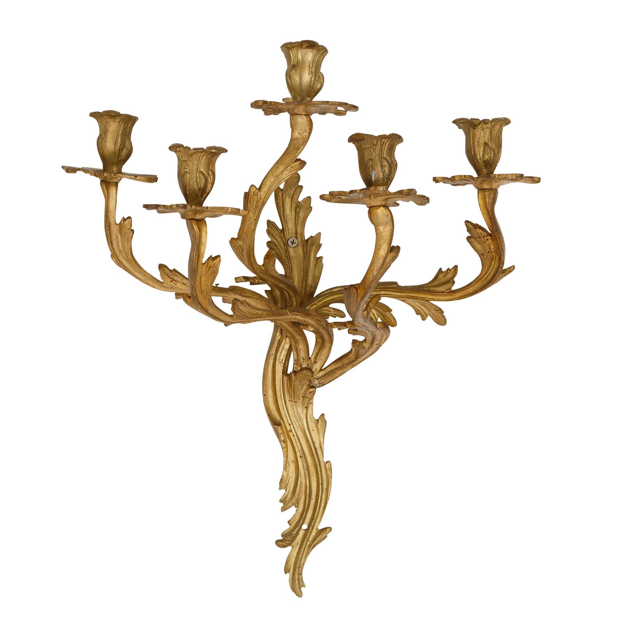 These beautiful gilt bronze (ormolu) wall sconces (lights) are designed in an elegant Rococo style after decorative arts of the Louis XV period (1715-1774). Characteristic of this style, they are composed of curved, asymmetrical organic forms.