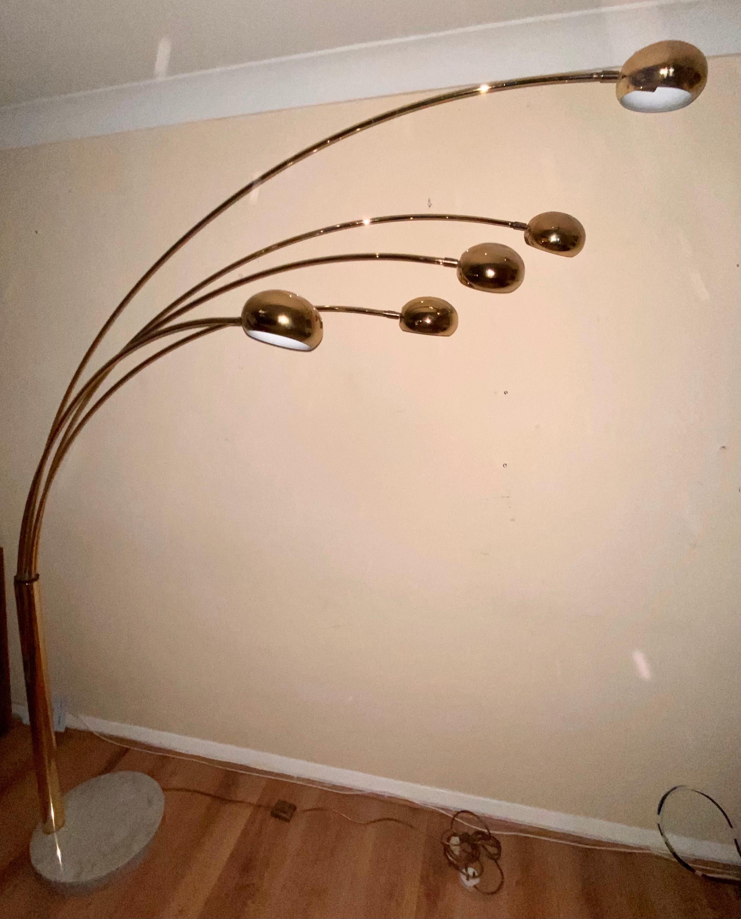 Floor lamp in gold-plated steel with five, articulating, ball shades each attached to an arched tubular arm that swings 360 degrees allowing all five arms to be placed in various positions. The lamp has a heavy round marble base at the bottom