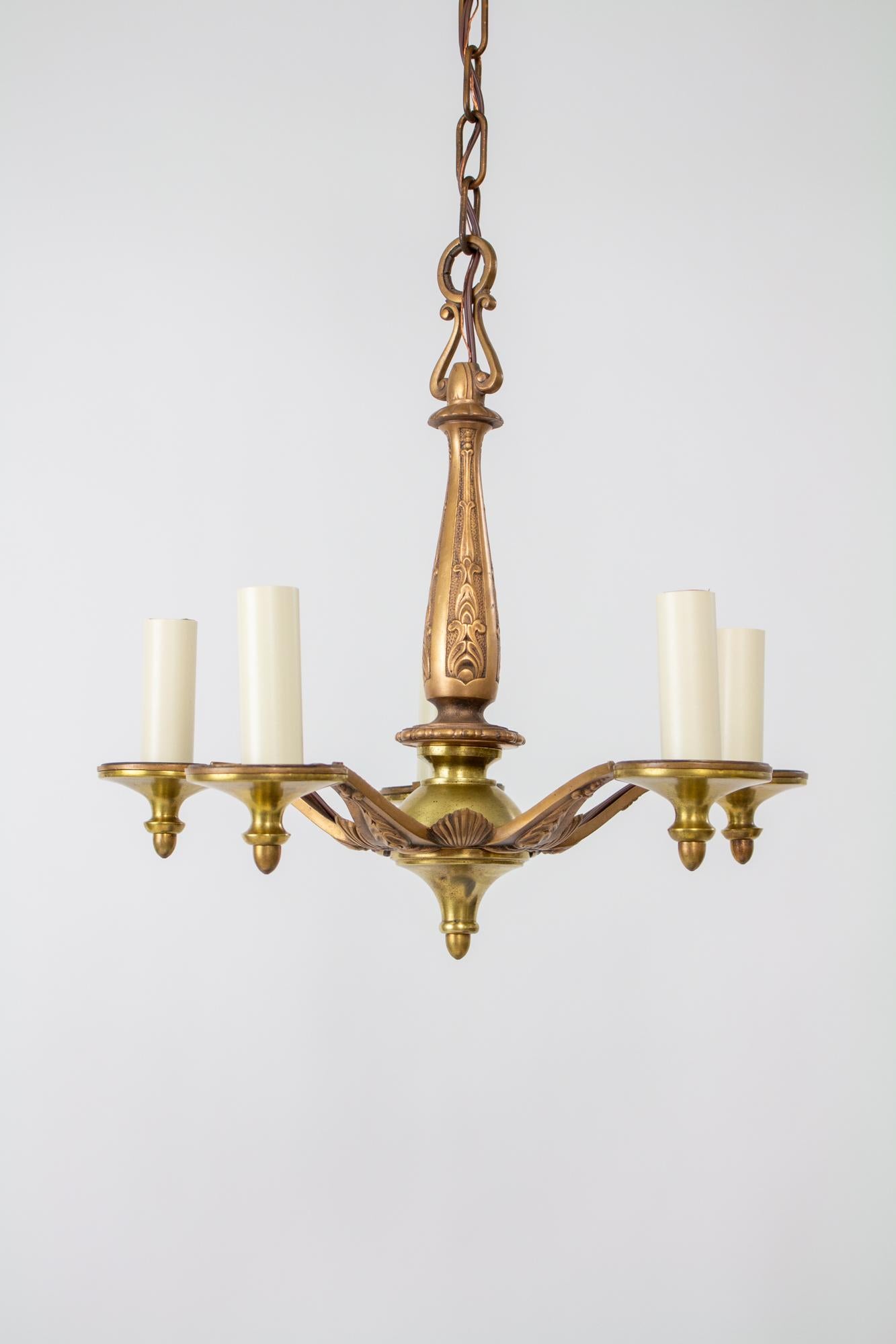 Five arm art deco cast bronze chandelier. cast bronze stem and arms with some brass stem elements. The casting is a geometric botanical design. Five arms and five lights. C. 1930. American. 

In very good condition, metals have been cleaned, fixture
