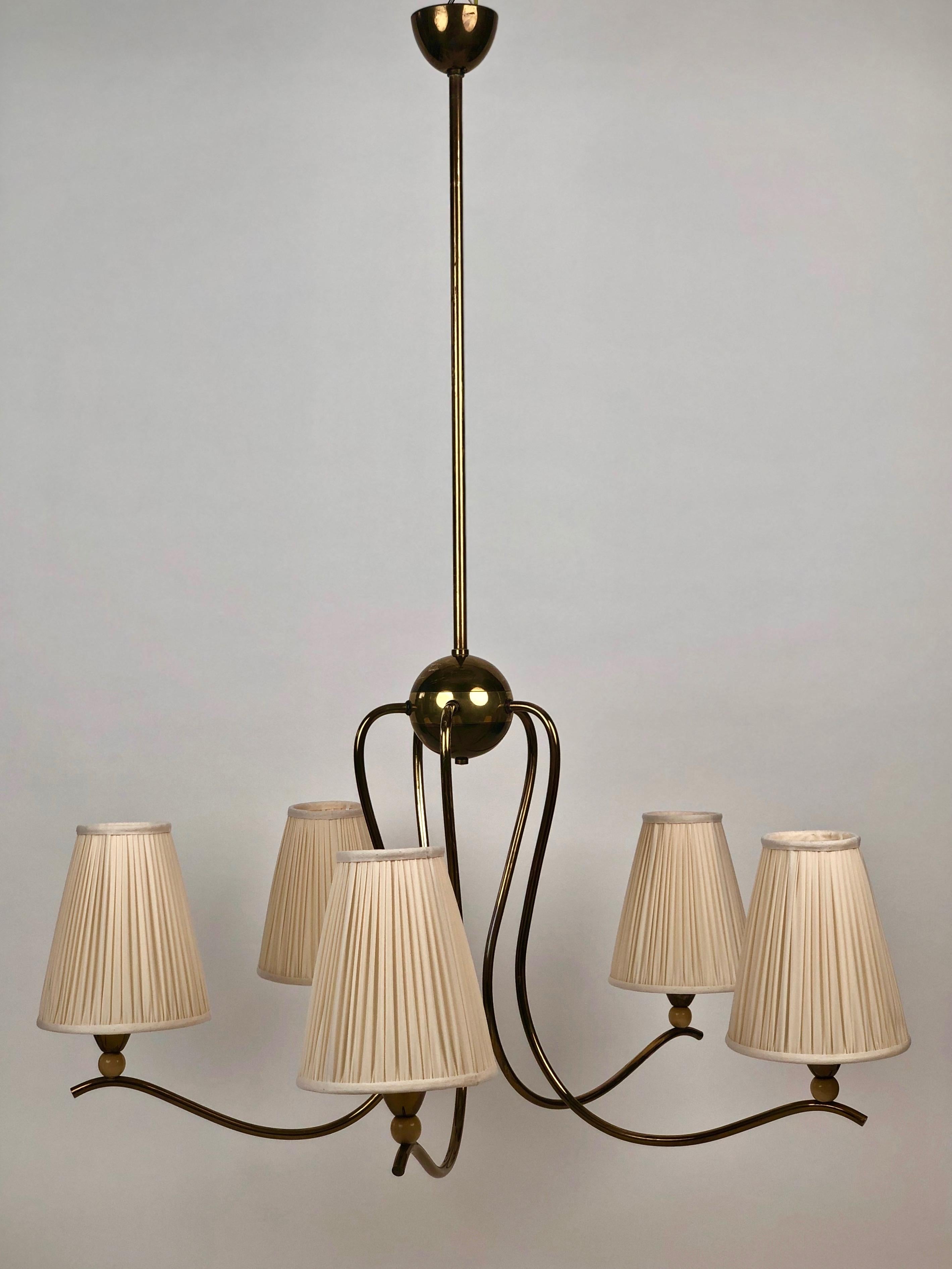 A large chandelier from Josef Frank, dating about 1925, Austria.
From the central ball flow five brass arms whose ends with brass fixtures for the shades.
Under the brass fixtures are placed small wooden balls, lacquered in creme colour.
This