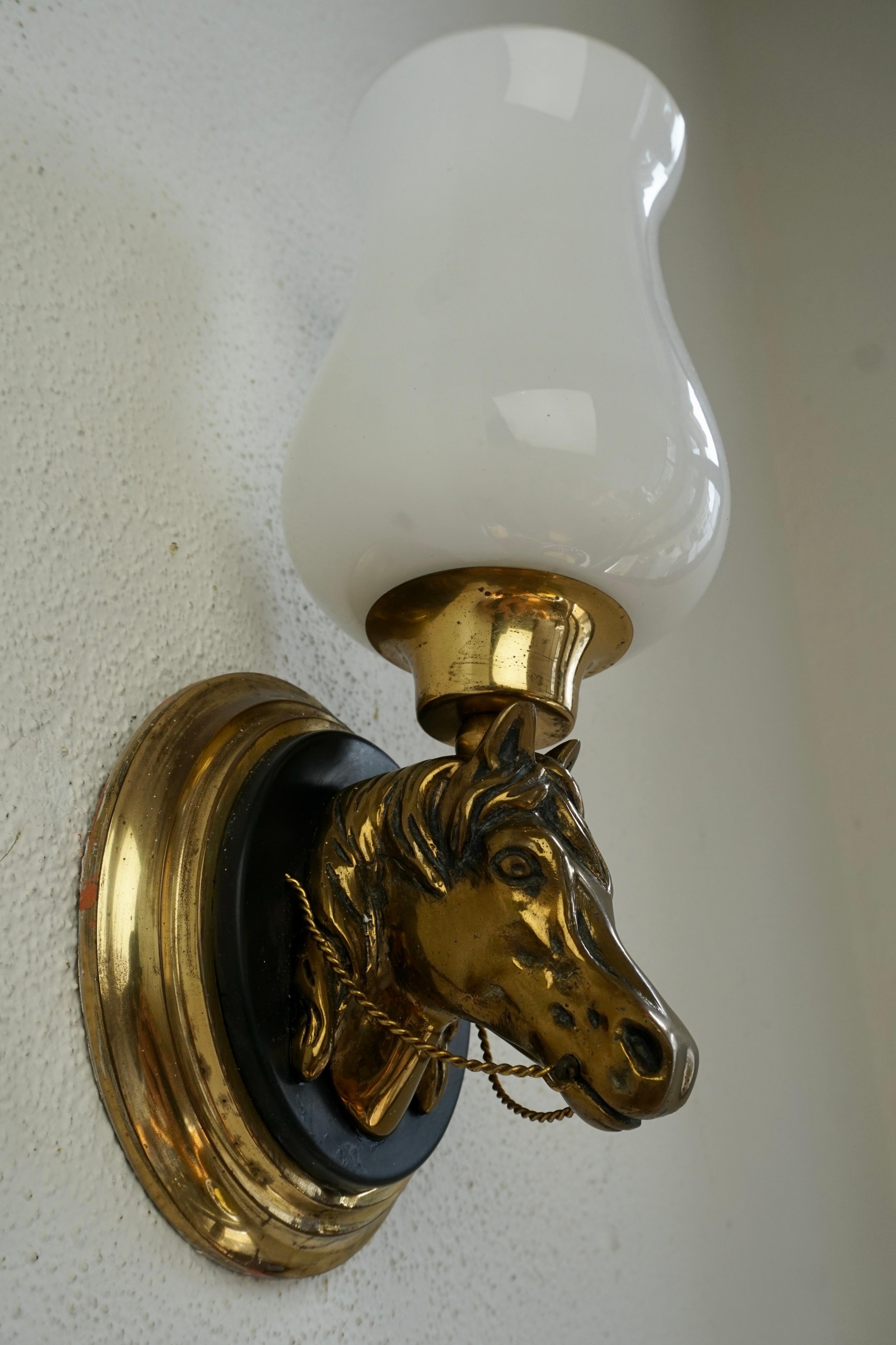 Five of 1950's bronze horse head wall sconces with white opaline glass shades.