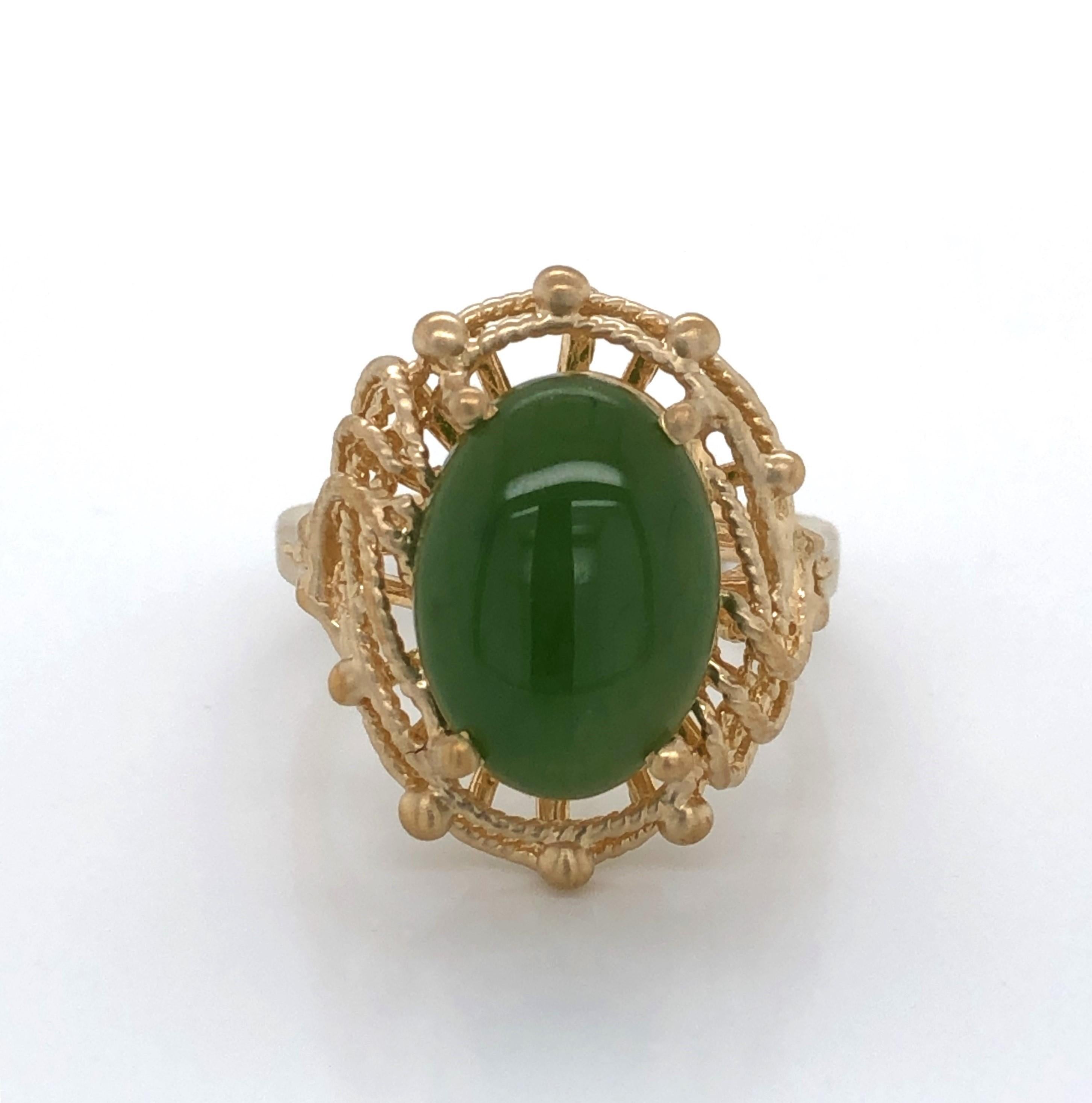 Twists of fourteen karat 14K yellow gold beautifully frame the soft green five carat jade cabochon oval stone that is the feature  of this stylish ring.
 In size 7 ring and sizable. Gift Boxed.