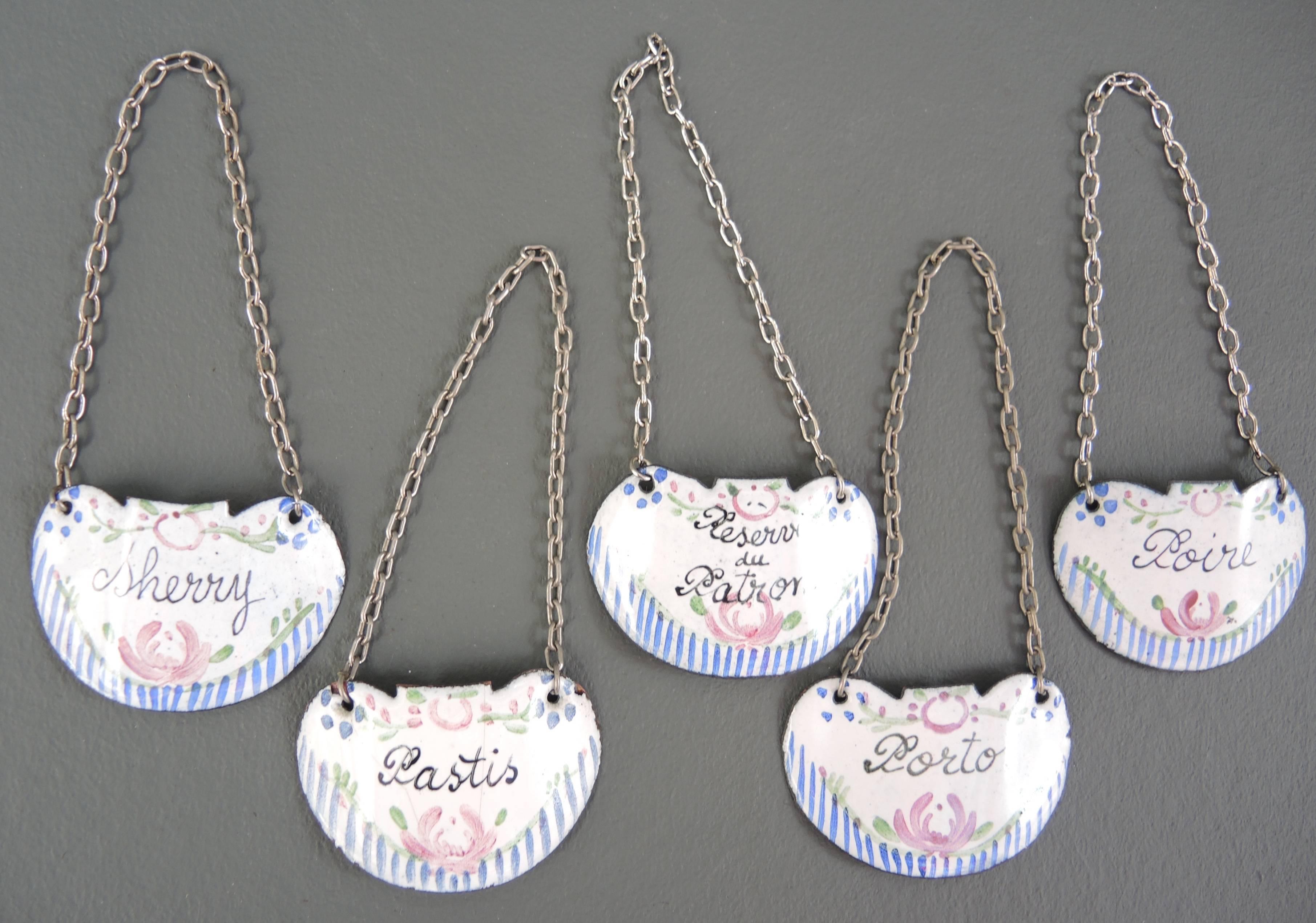 A very special set of five French decanter tags or bottle labels handmade in baked enamel on copper with silver chains, 19th century. 
 The beautifully hand written enameled labels read: Pastis, Sherry, Porto, Poire (pear liqueur) and Reserve du