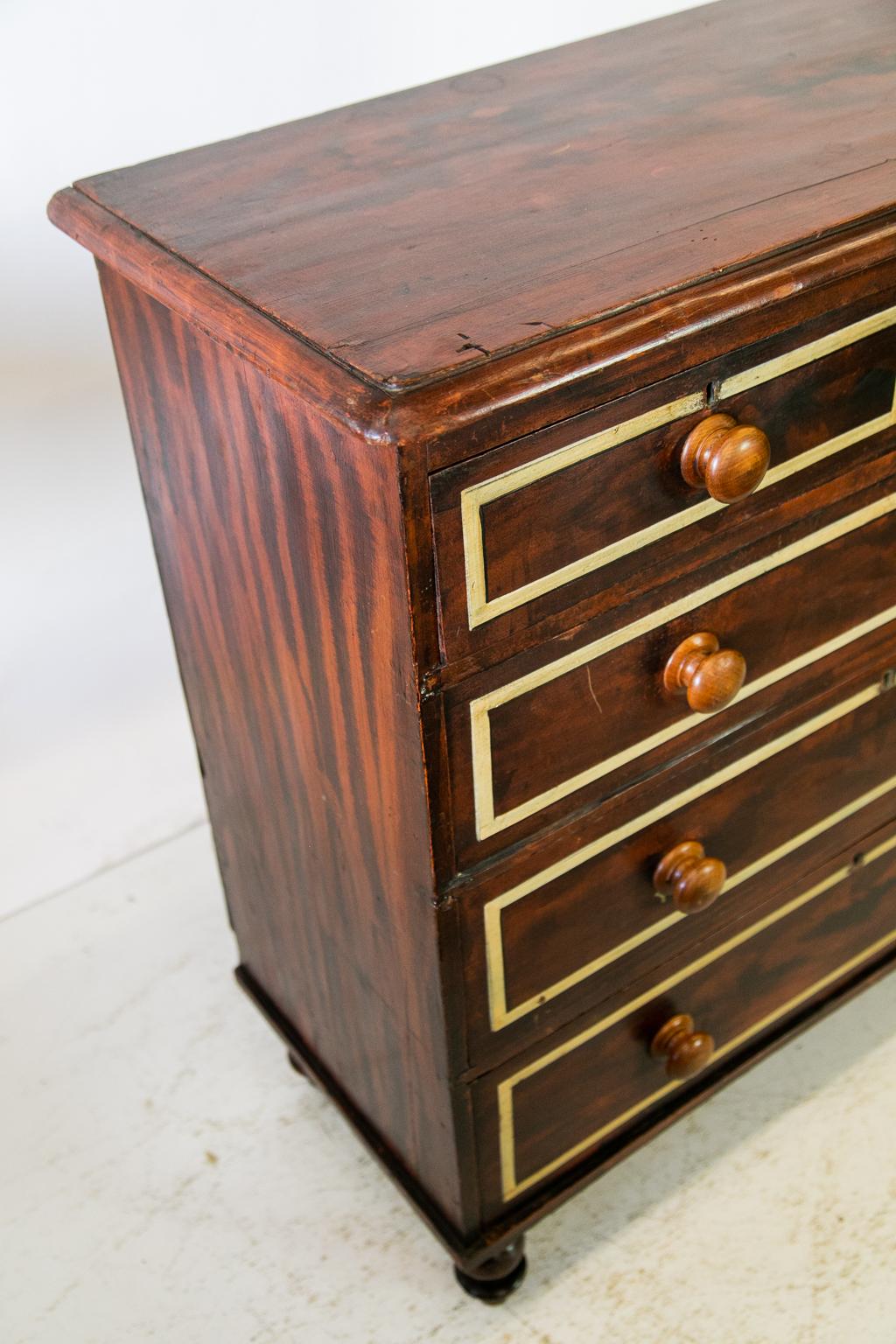 Five-drawer English faux painted chest, is painted to look like wood grain with light bindings on the drawer fronts. The sycamore knobs and bun feet are original.