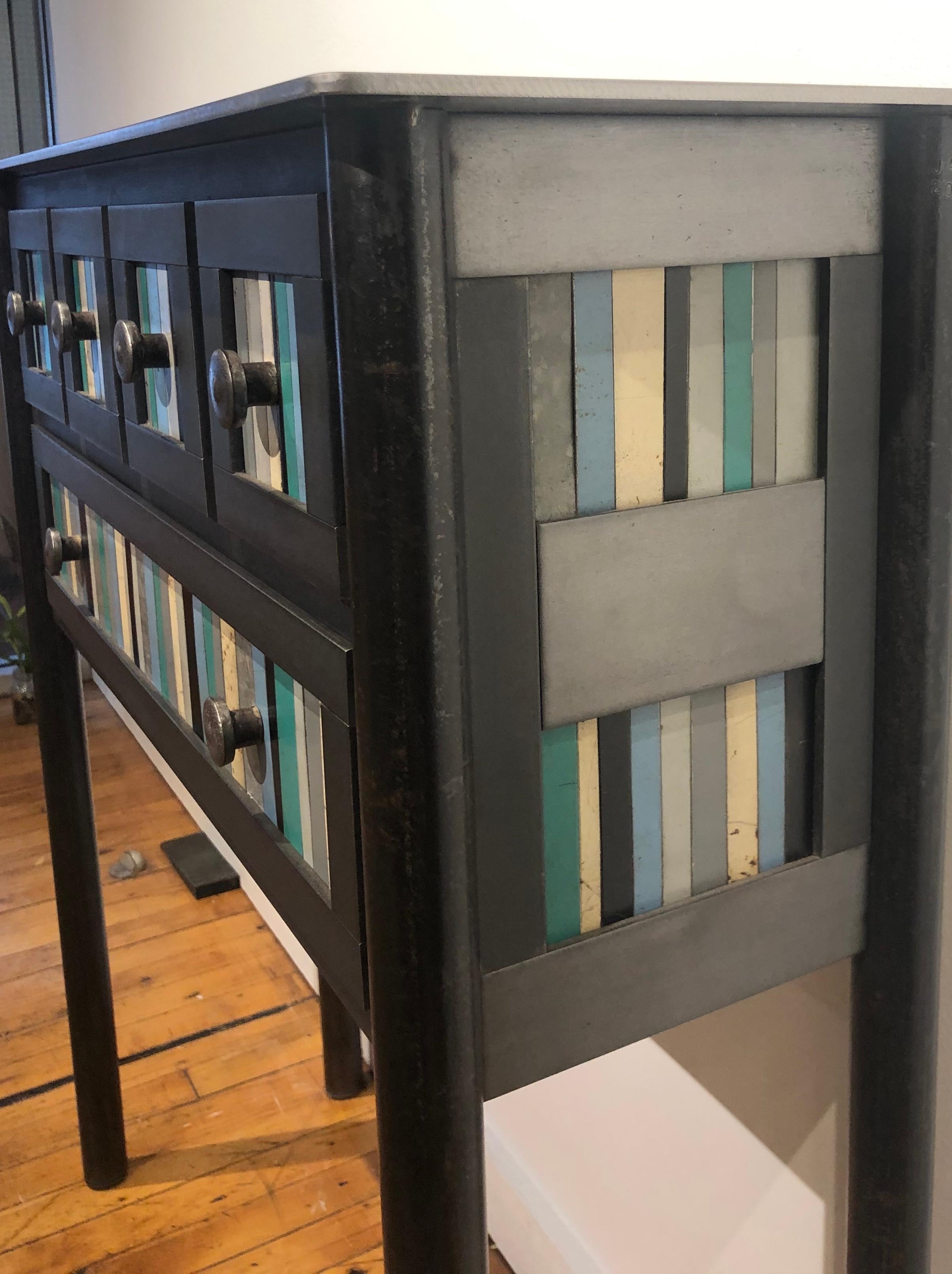 This modern 5-drawer table is made from hot roll blue steel with the front panel design based on the Gees Bend Quilts. Each panel is unique with the use of galvanized rusted steel that is salvaged. Its rich grey, blue and green tones enhance the