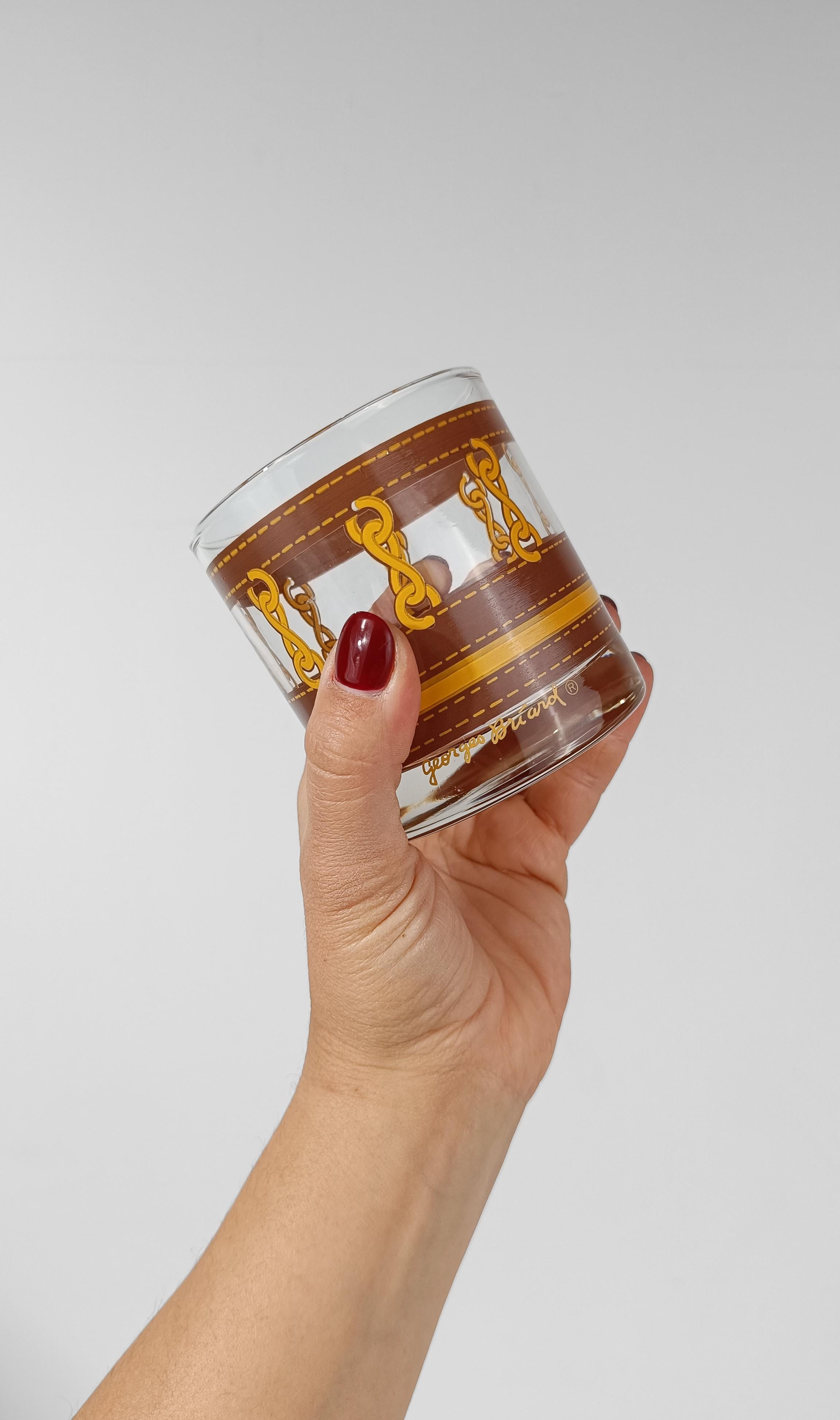 Set of glasses designed by Georges Briar, decorated with silkscreen depicting golden chains connecting flaps of cognac stitched leather.
This set of highly decorative glasses is the classic whiskey glass, the Lowball perfect for serving cocktails