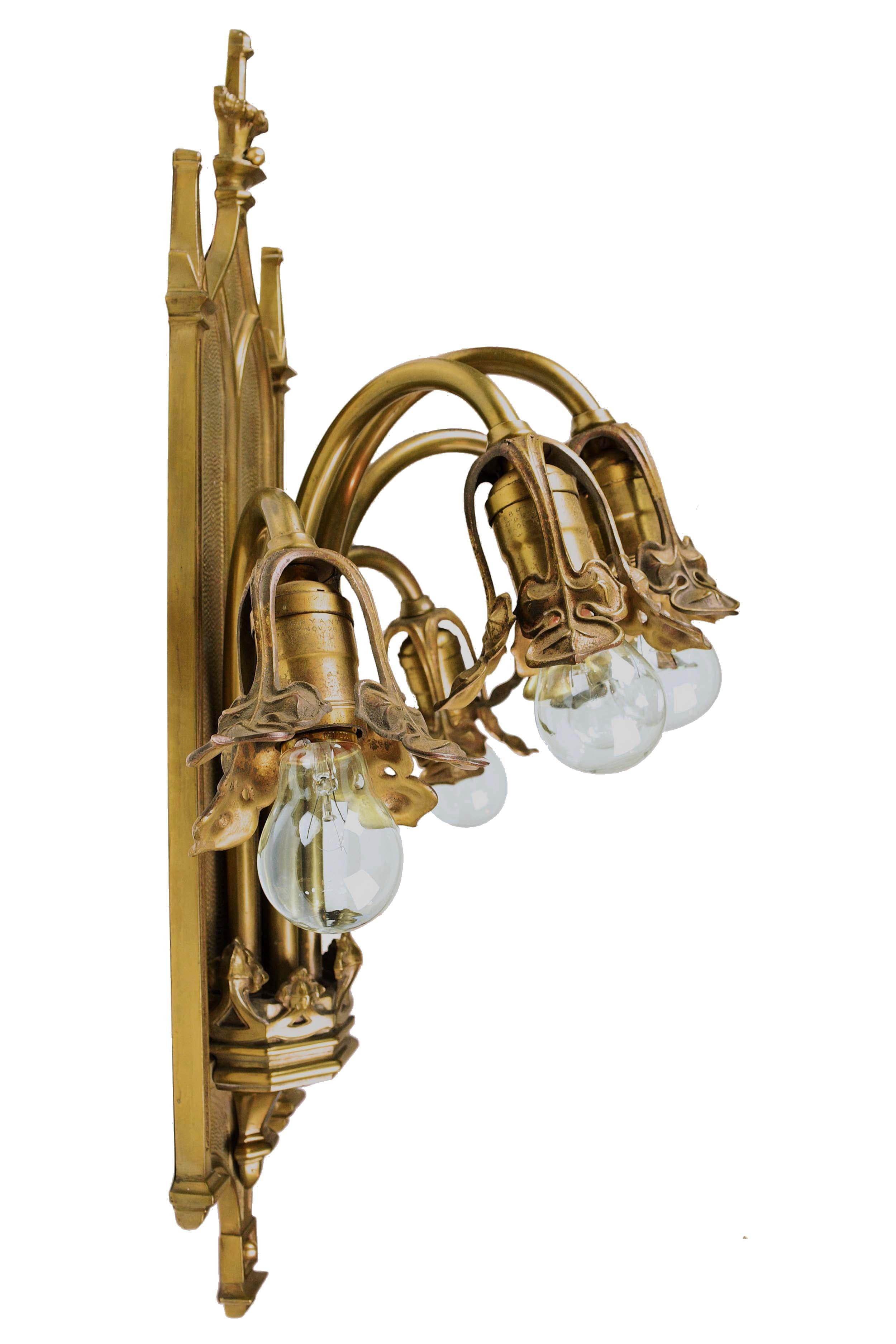 This large Gothic cast brass sconce is absolutely stunning. The design is inspired by nature and is decorated with leaf-like shapes around the sockets. A Gothic style back plate juxtaposes the organic shapes. It was manufactured by Bradley and