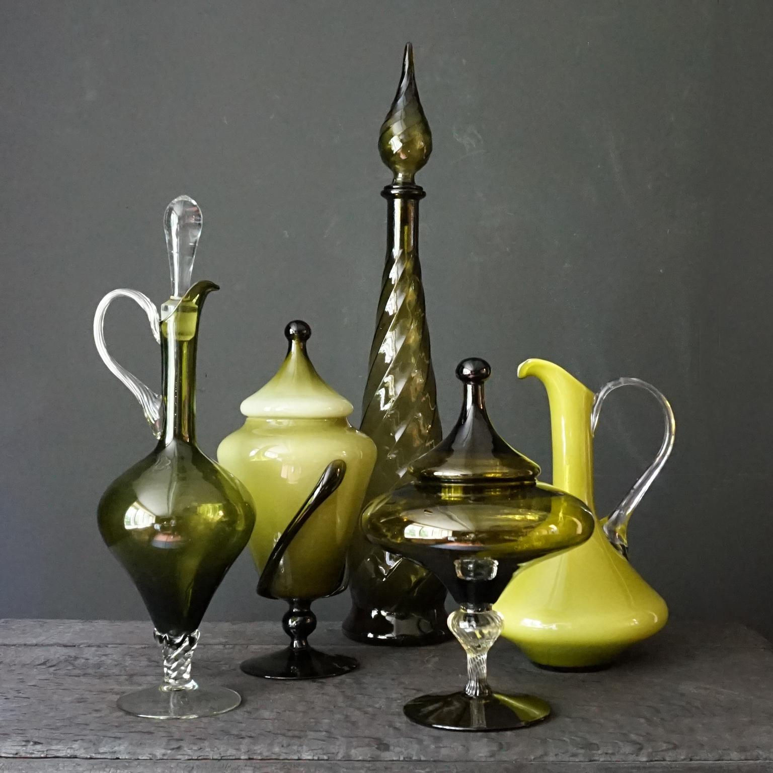 Very decorative olive green set of five different size Italian blown and pressed glass bottles.
One high pressed clear glass genie bottle, two blown glass carafes and two blown glass apothecary or candy jars.

Mention Italian glass and probably