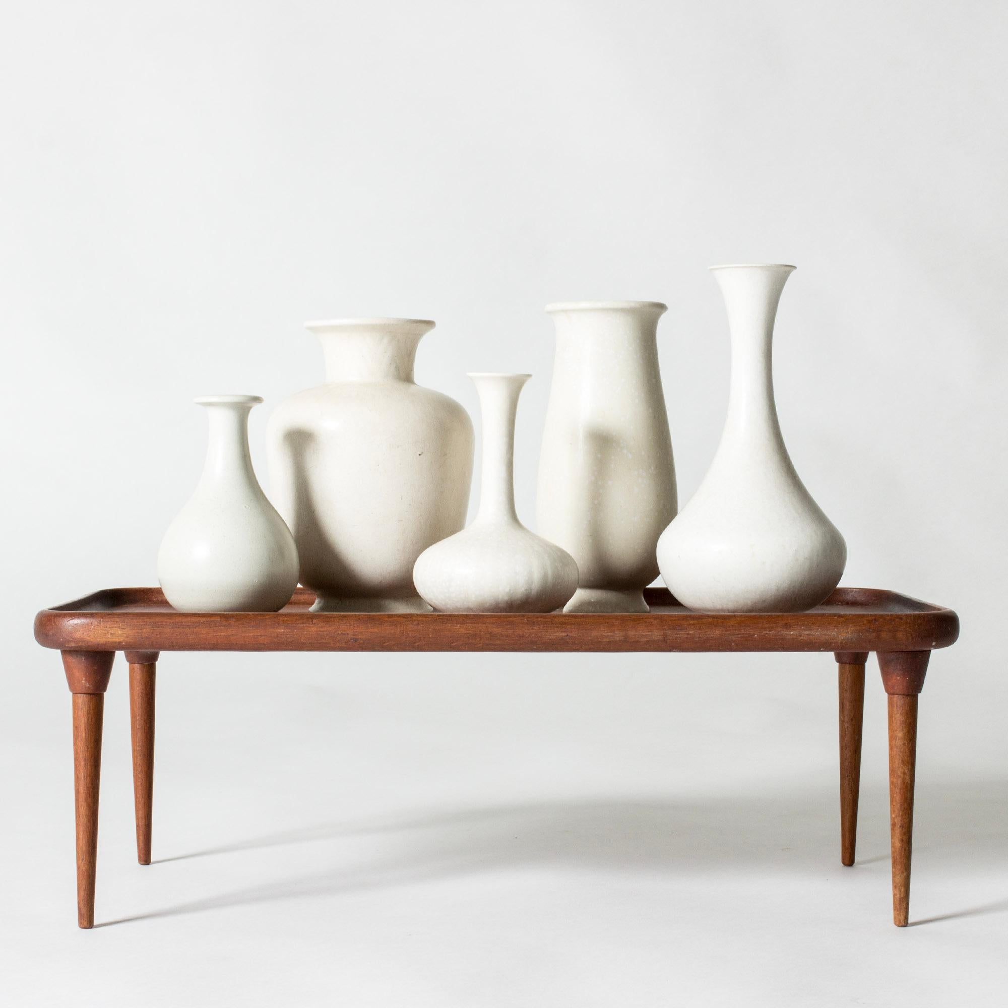Satz von fünf Vasen aus Steinzeug von Gunnar Nylund in verschiedenen eleganten, geschwungenen Formen und Größen. Alle sind schön eierschalenweiß glasiert.

Höhe 14/15,5/19/20/22,5 cm, Durchmesser 8-13,4 cm.

Gunnar Nylund war einer der