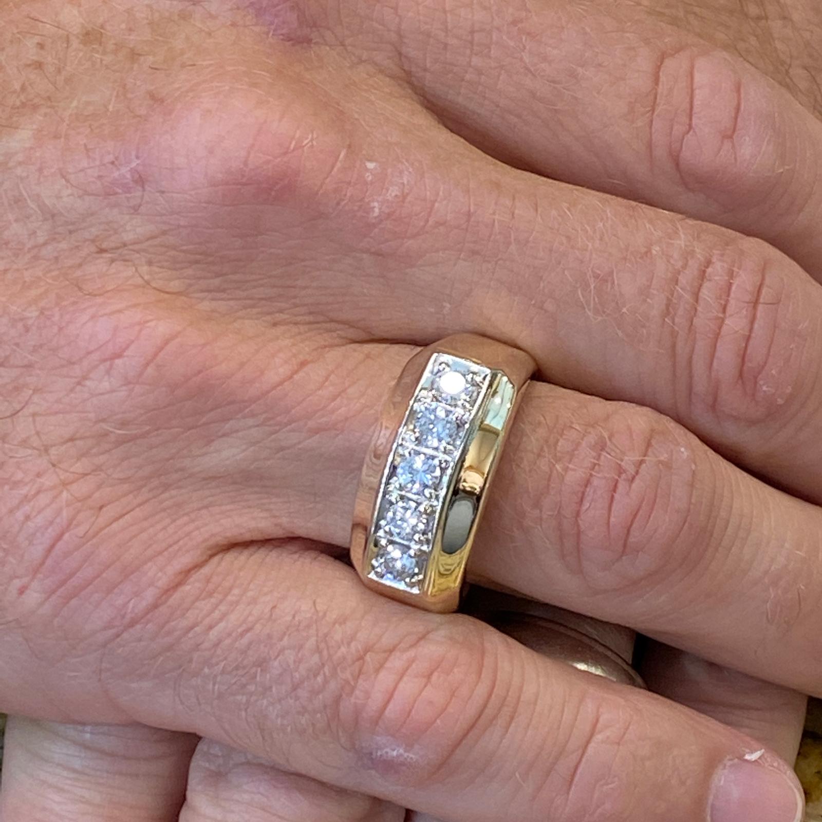Men's diamond band fashioned in 14 karat yellow gold. The ring features 5 round brilliant cut diamonds weighing 1.00 carat total weight and graded H-I color and SI clarity. The band measures 10mm in width, and is currently size 12.5 (can be sized).