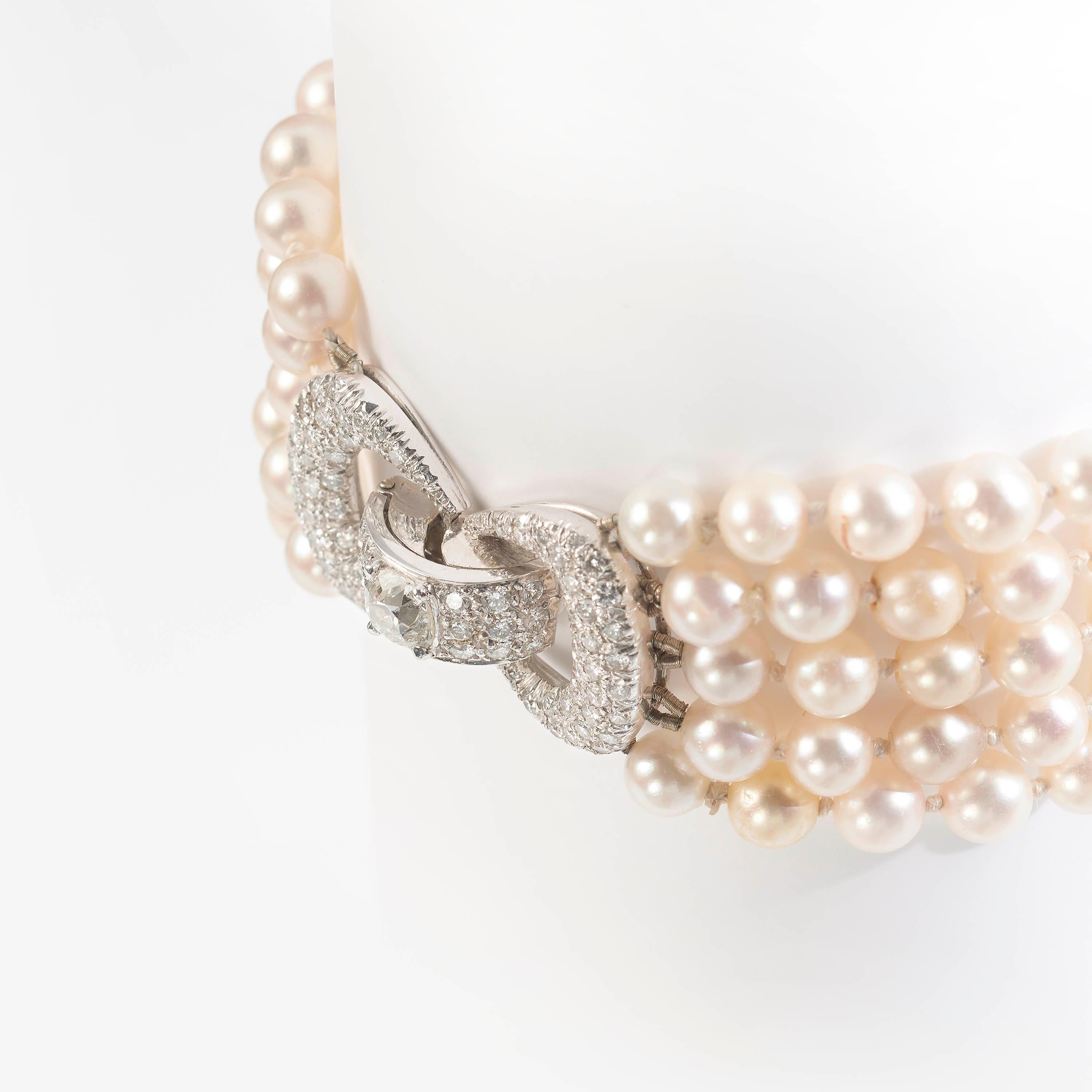 A multi-row pearl and diamond bracelet, consisting of five strung rows of white cultured pearls, measuring approximately 5mm each, terminating in a diamond-set bow design clasp, mounted in white gold, set with a central old-cut cushion shaped